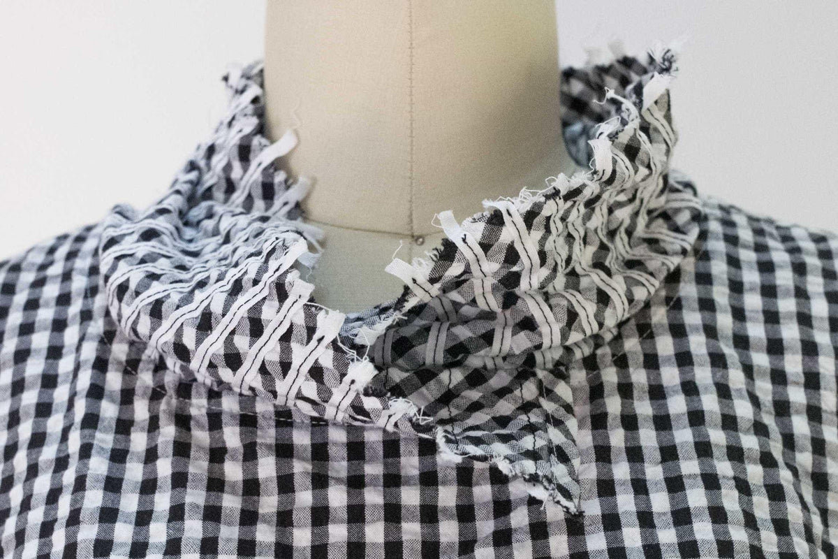 Black and white gingham fabric with frayed ruffle collar on mannequin, ideal for sewing apparel or quilting projects.