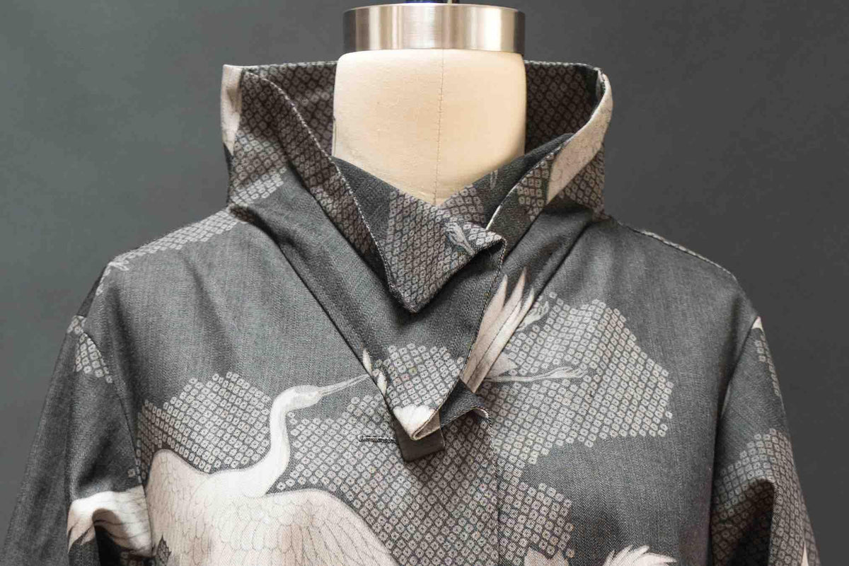 Gray fabric with white crane print and geometric pattern, styled on mannequin for apparel sewing