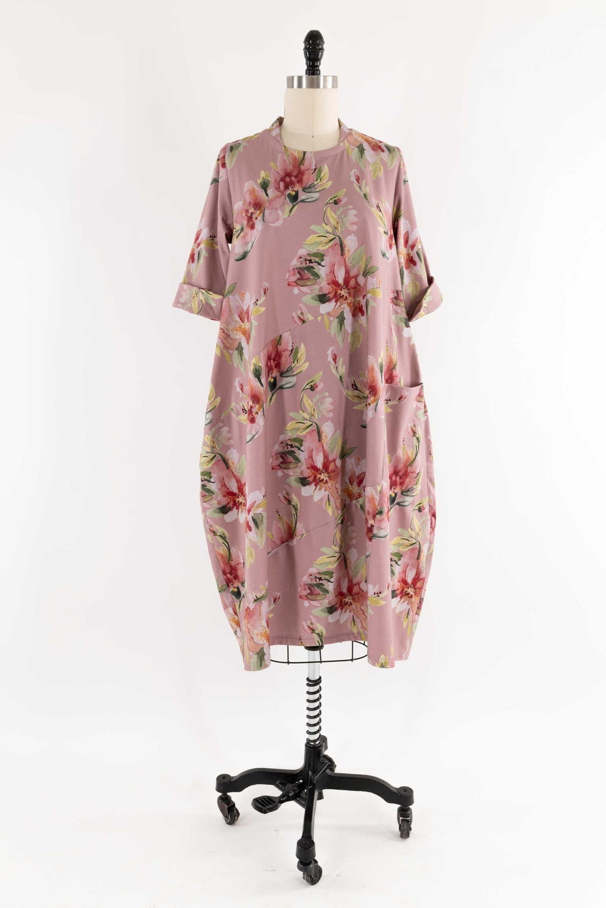 Pink floral print dress with rolled sleeves and side pockets on mannequin, ideal for sewing projects