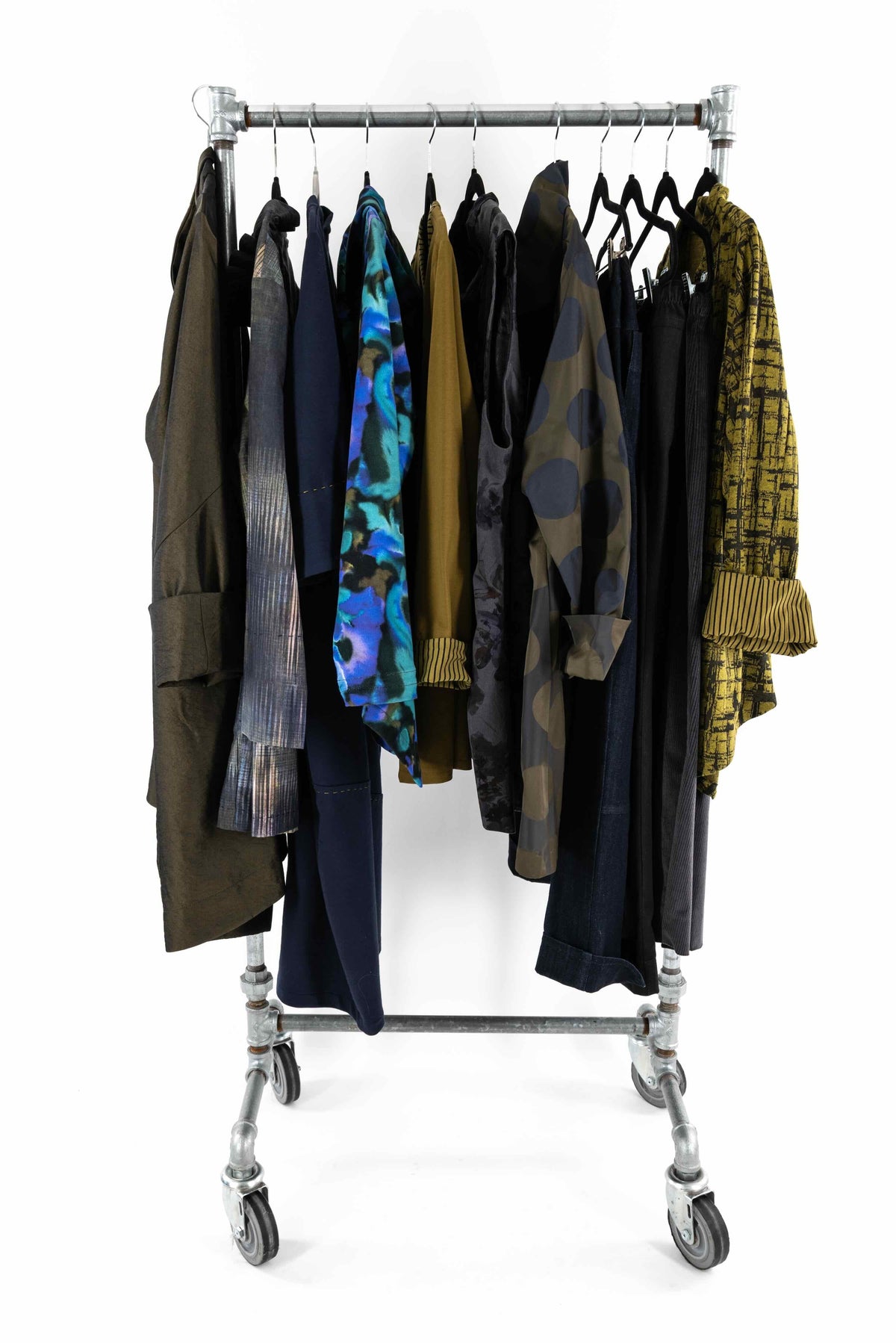 Assorted fashion fabrics on a rolling rack, featuring prints, solids, and textures for apparel sewing