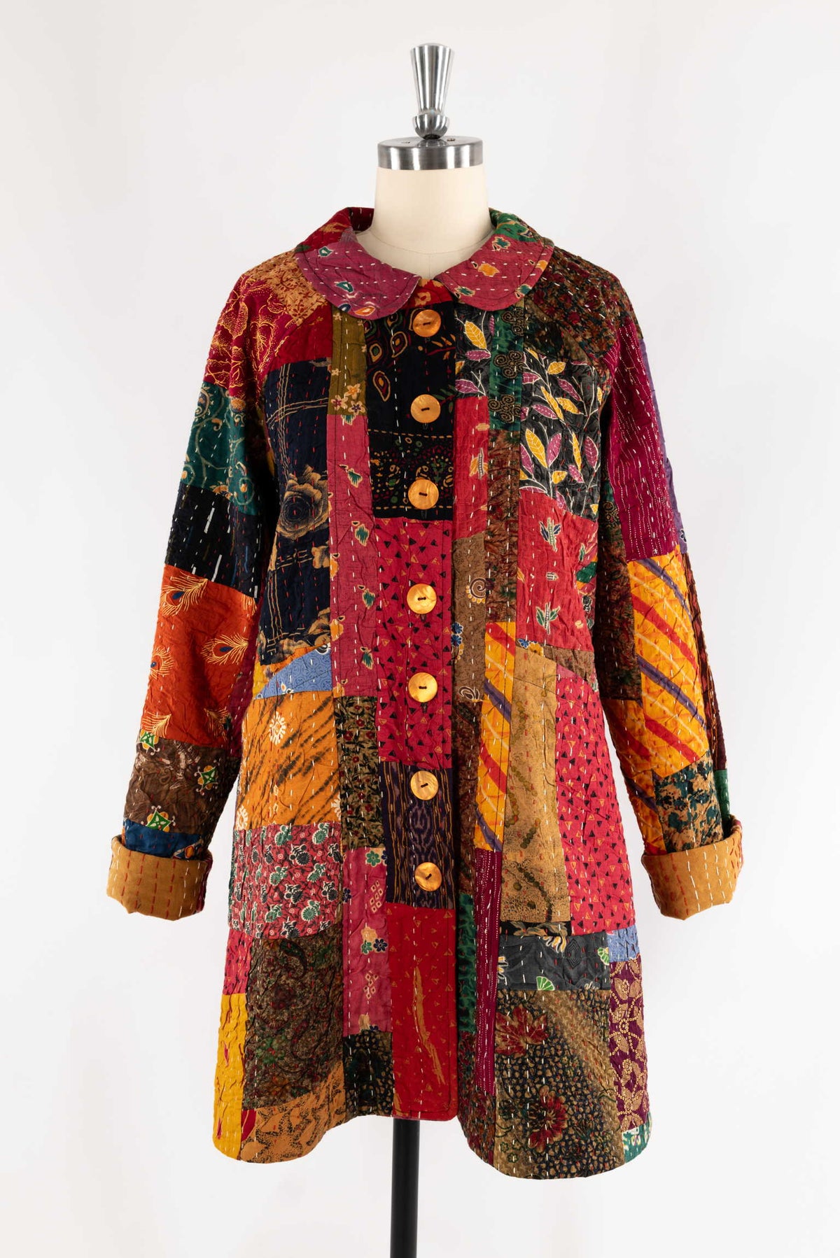 Colorful patchwork quilted coat with floral and geometric prints, button front, on mannequin