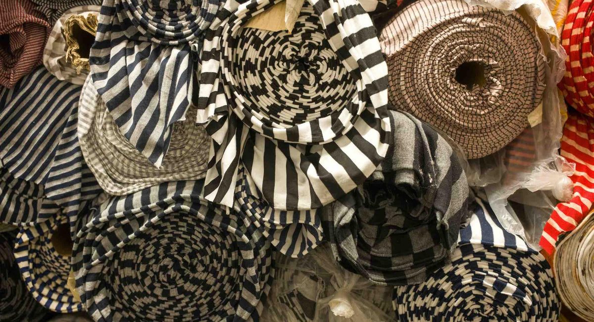 Assorted striped and checkered fabric rolls in black, white, and red for sewing and apparel projects