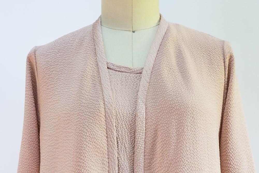 Soft pink textured knit fabric draped on mannequin, ideal for apparel sewing projects