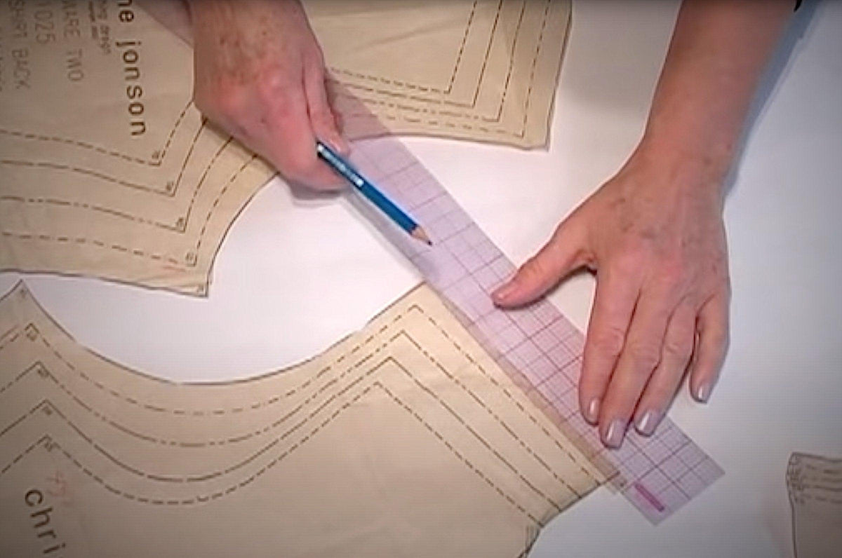 Hands measuring and marking fabric with ruler and pencil for sewing patterns