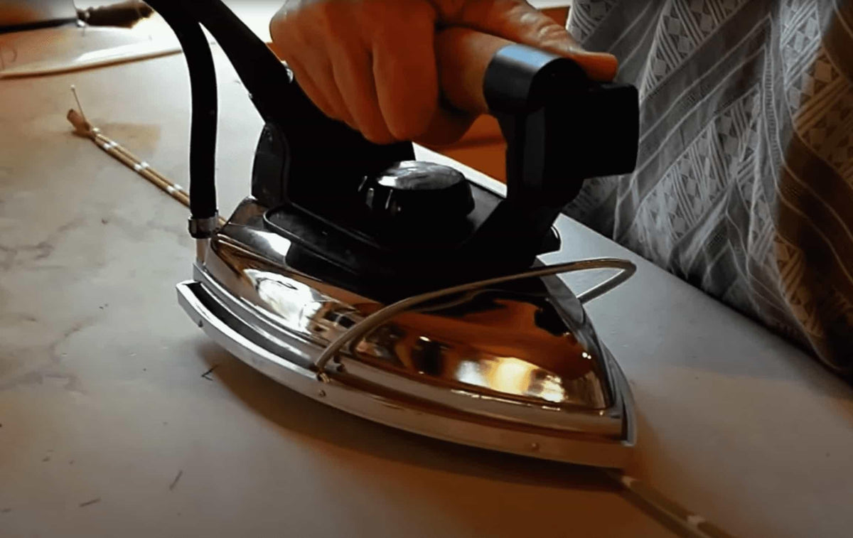 Hand ironing fabric with vintage steam iron on ironing board