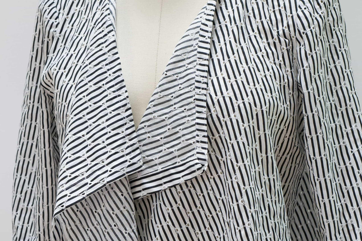 Black and white striped eyelet fabric for apparel sewing, featuring geometric cutouts and soft drape