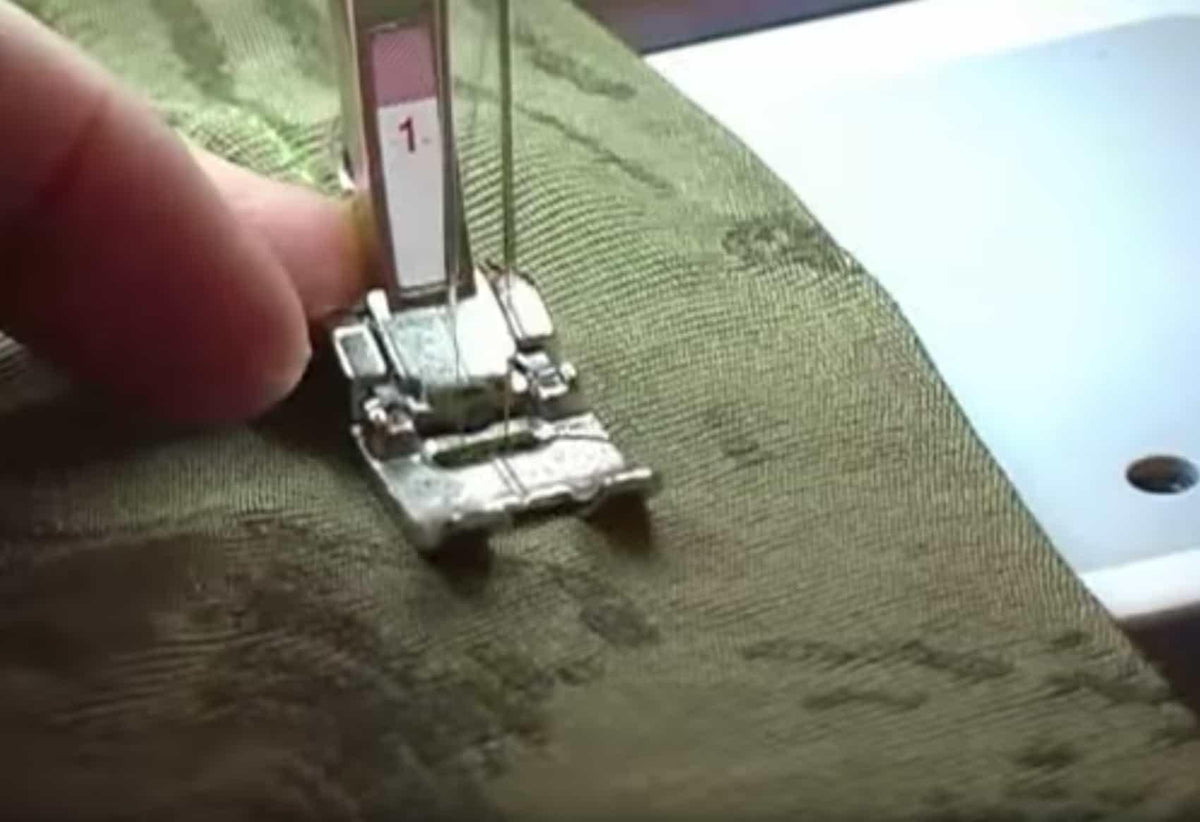 Sewing machine foot stitching olive green textured fabric for apparel or quilting projects