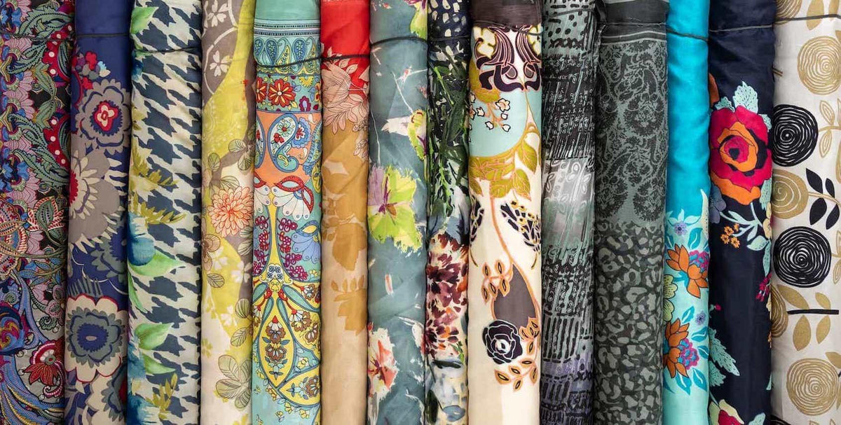 Colorful fabric bolts with floral, paisley, and abstract prints for sewing and quilting projects