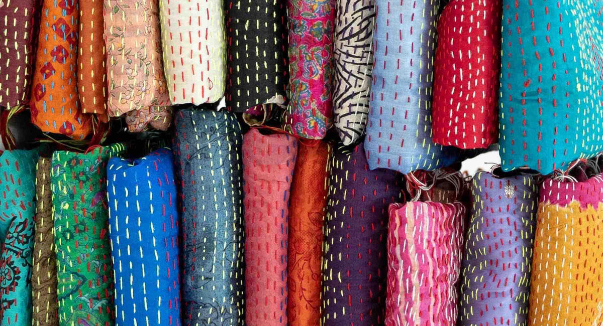 Colorful fabric bolts with kantha stitch patterns, ideal for sewing apparel and quilting projects
