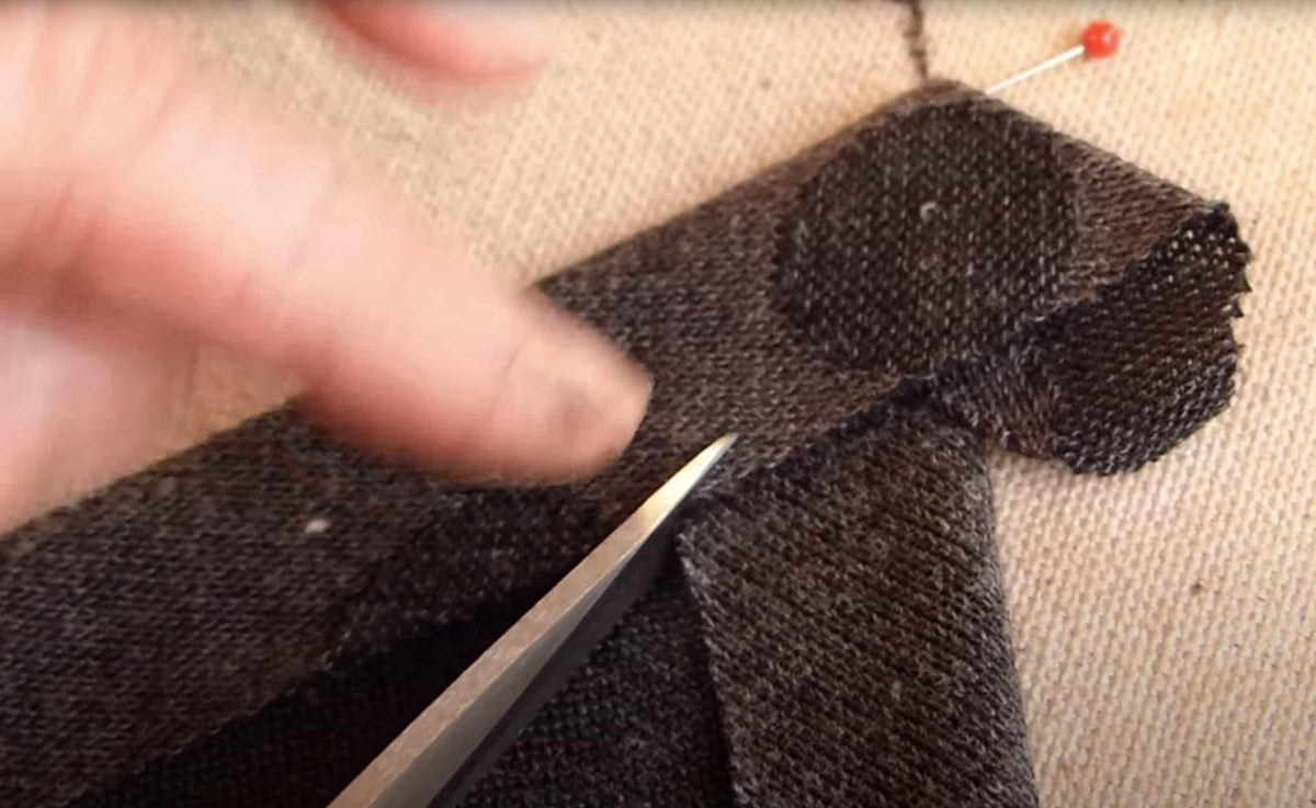 Cutting dark textured knit fabric with scissors for sewing projects