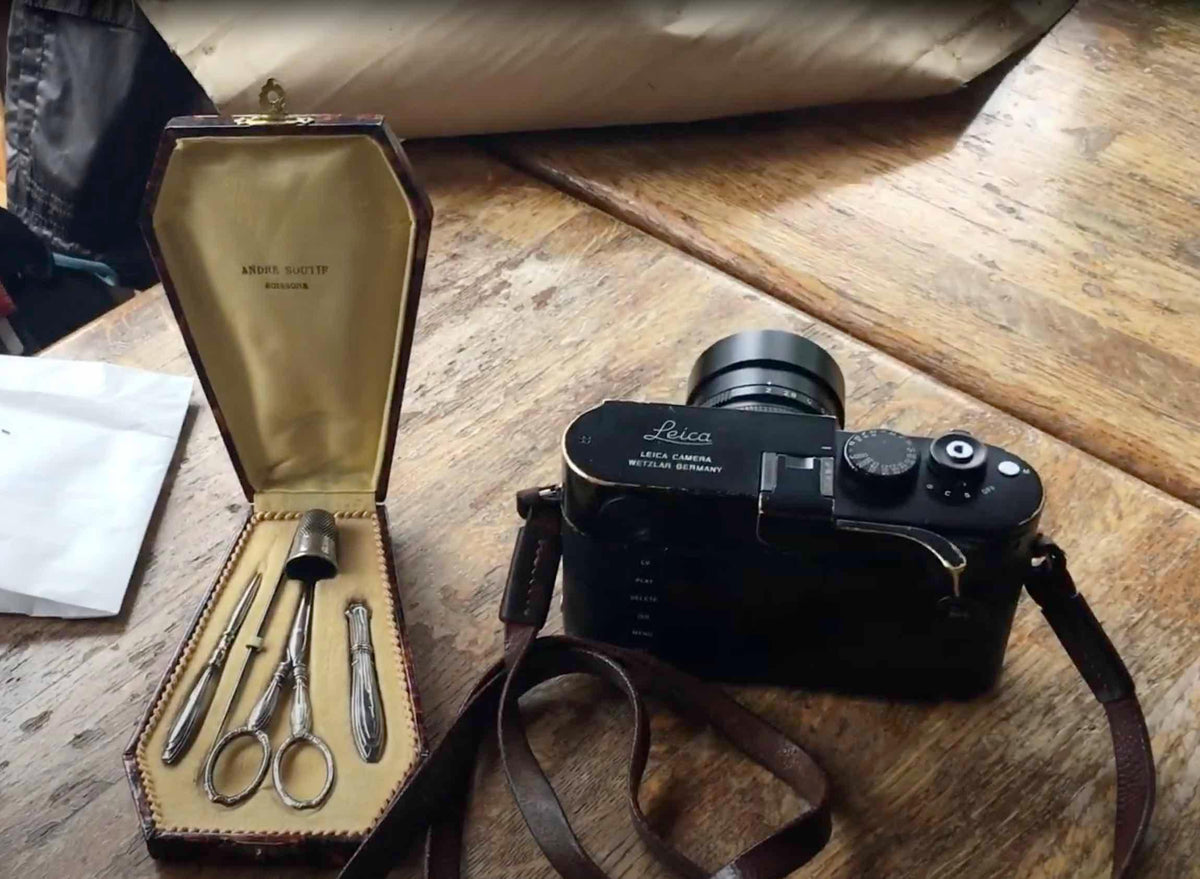 Leica camera and vintage sewing kit on rustic wood table