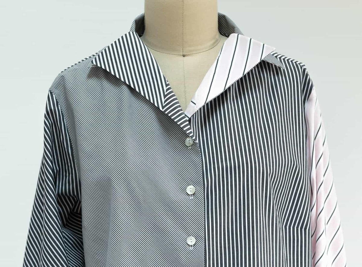 Black and white striped shirt with pink sleeve detail, button-front design on mannequin