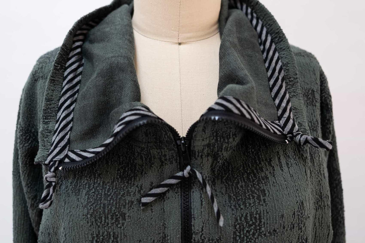 Dark green textured knit jacket with striped hood lining and zipper detail, ideal for sewing apparel projects.