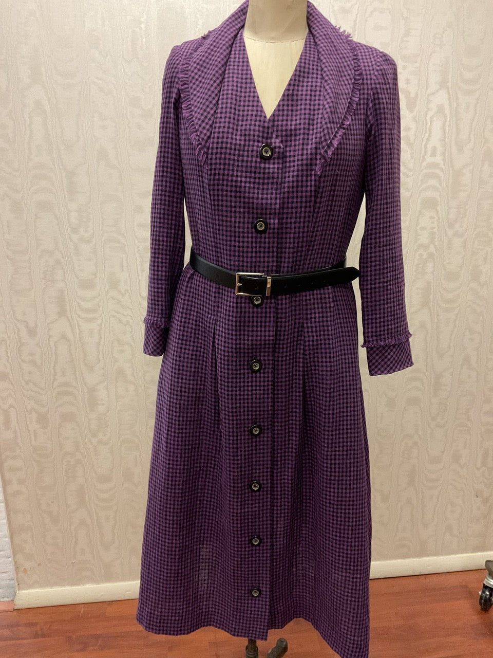 Purple gingham button-front dress with ruffled collar and black belt, ideal for sewing projects