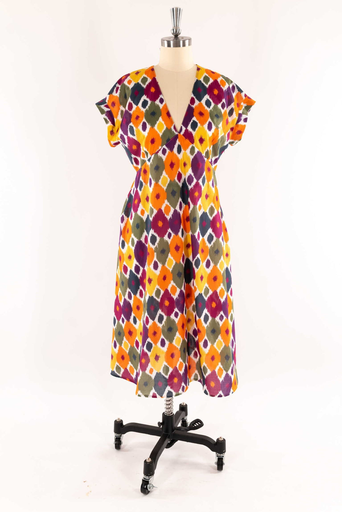 V-neck dress with colorful geometric ikat print on mannequin, ideal for sewing apparel or quilting projects
