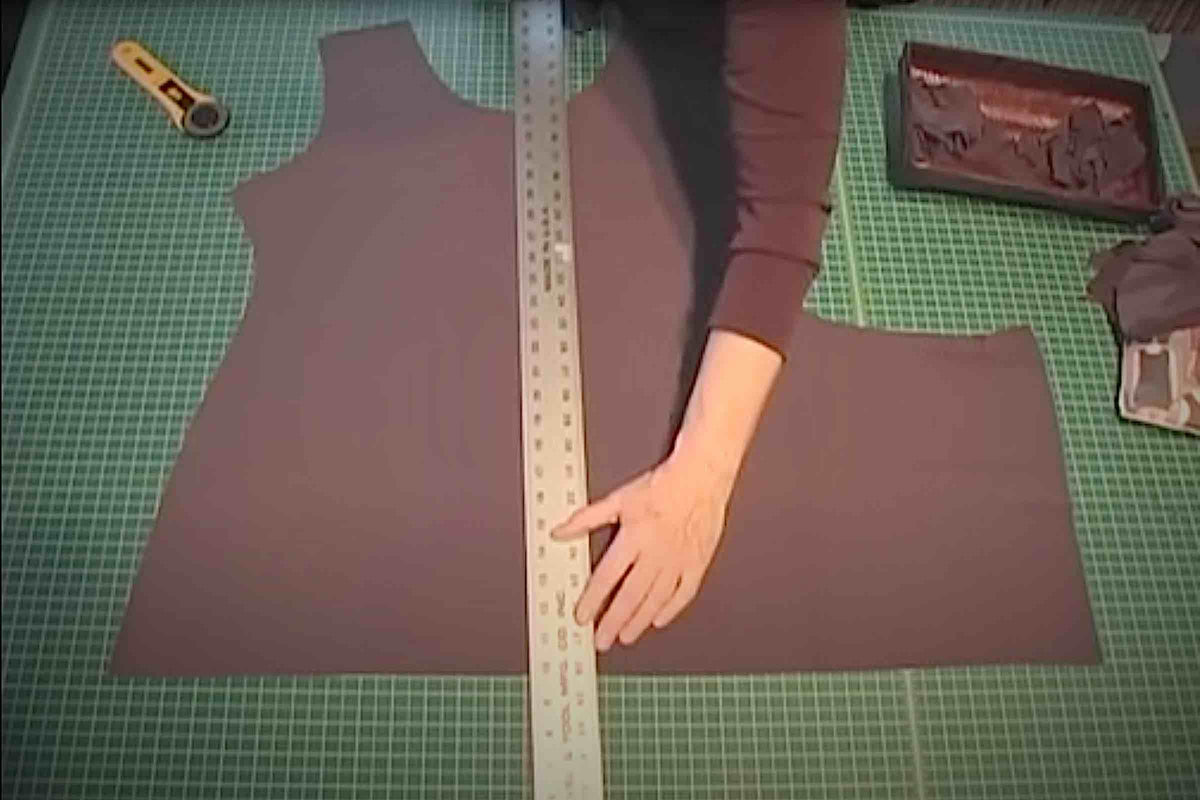 Cutting brown fabric on green mat with ruler for sewing projects