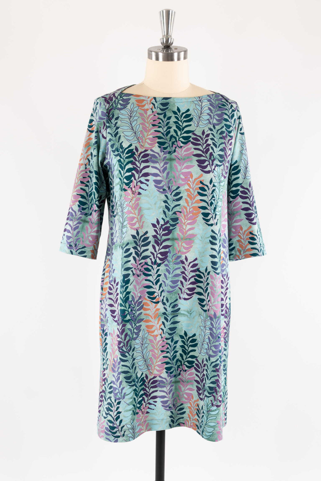 Floral print dress with 3/4 sleeves on mannequin, featuring colorful leaf pattern on teal fabric for sewing projects
