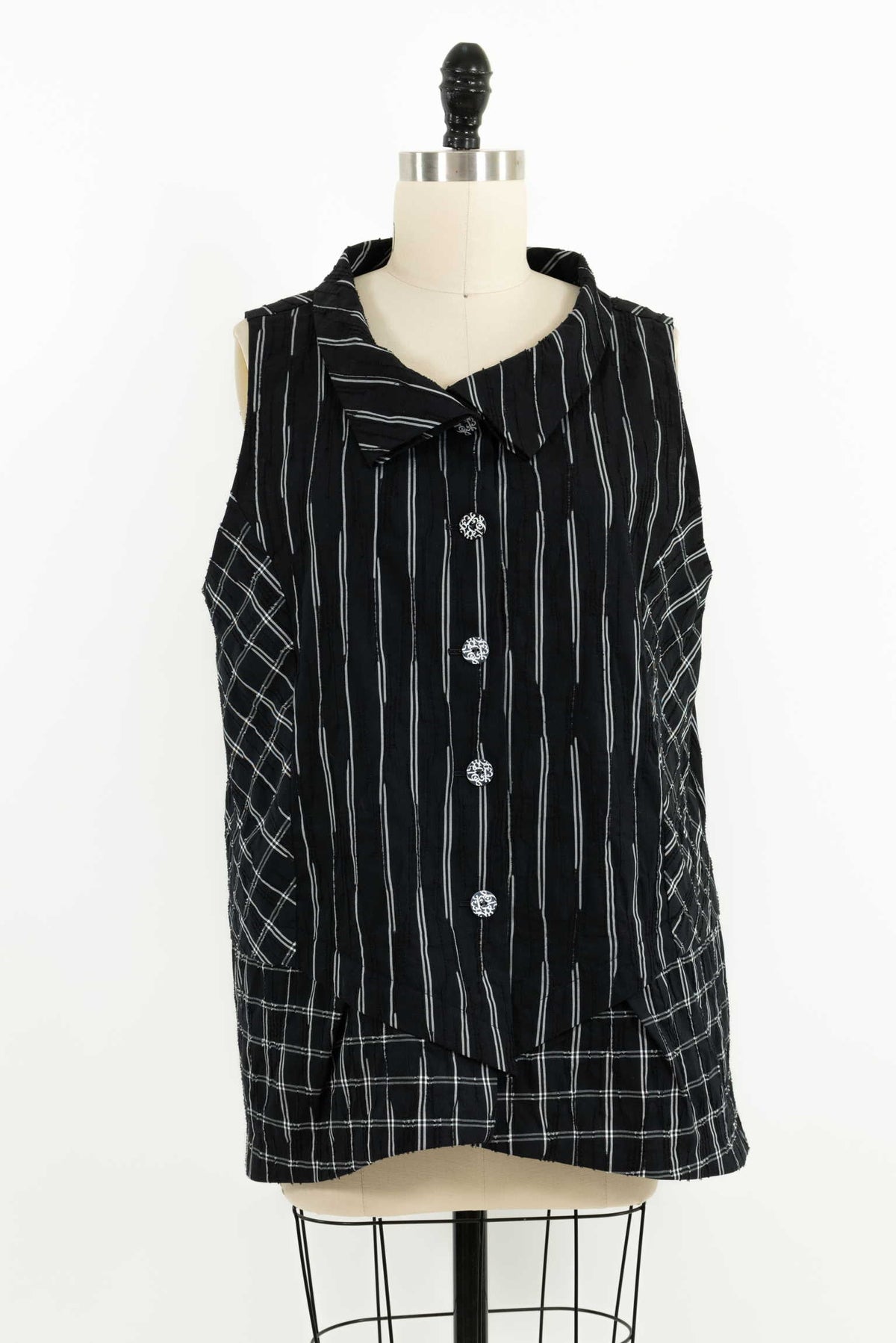 Black and white striped sleeveless top with decorative buttons and plaid accents on mannequin