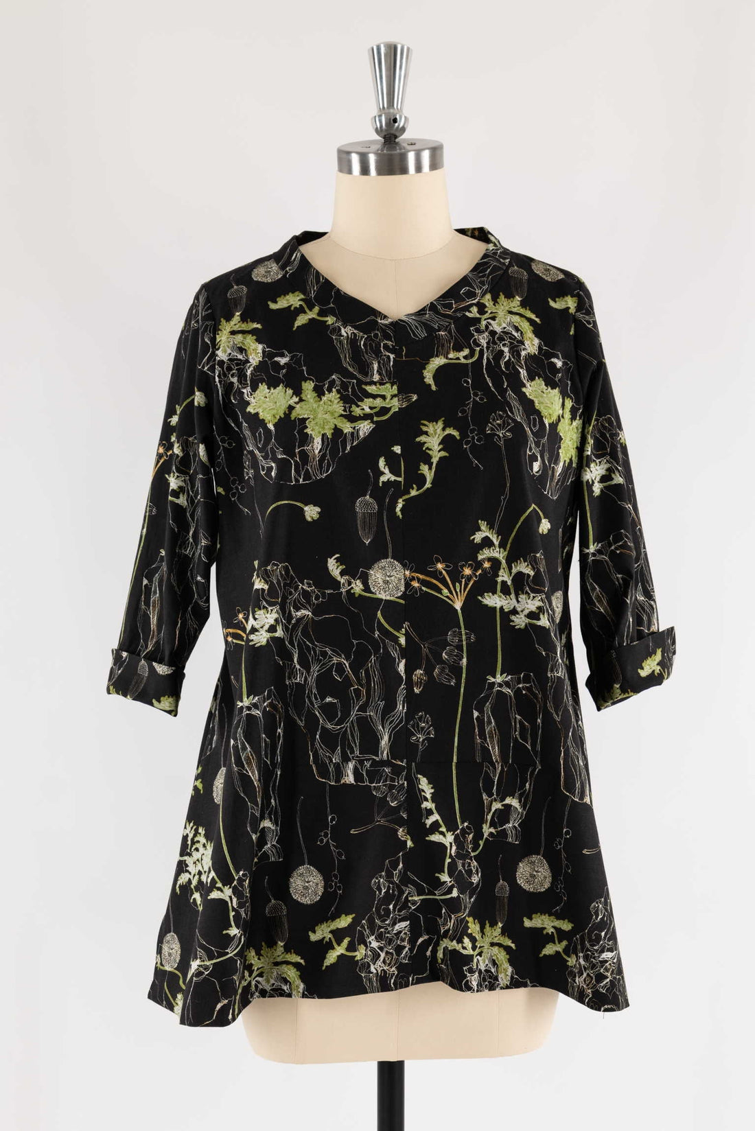 Black floral print tunic with green botanical design, 3/4 sleeves, V-neck, displayed on mannequin