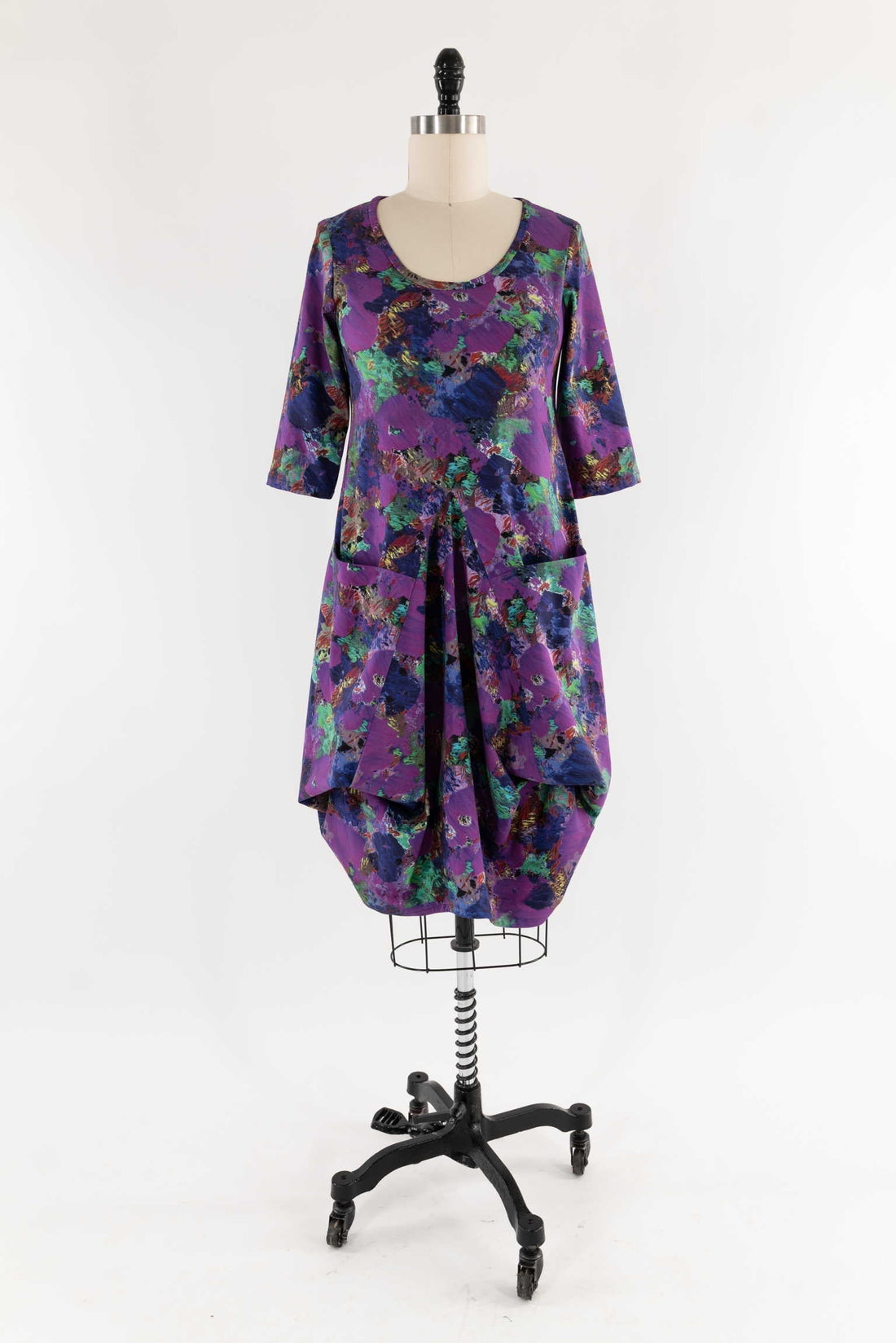 Purple abstract print dress with 3/4 sleeves and front pockets on mannequin