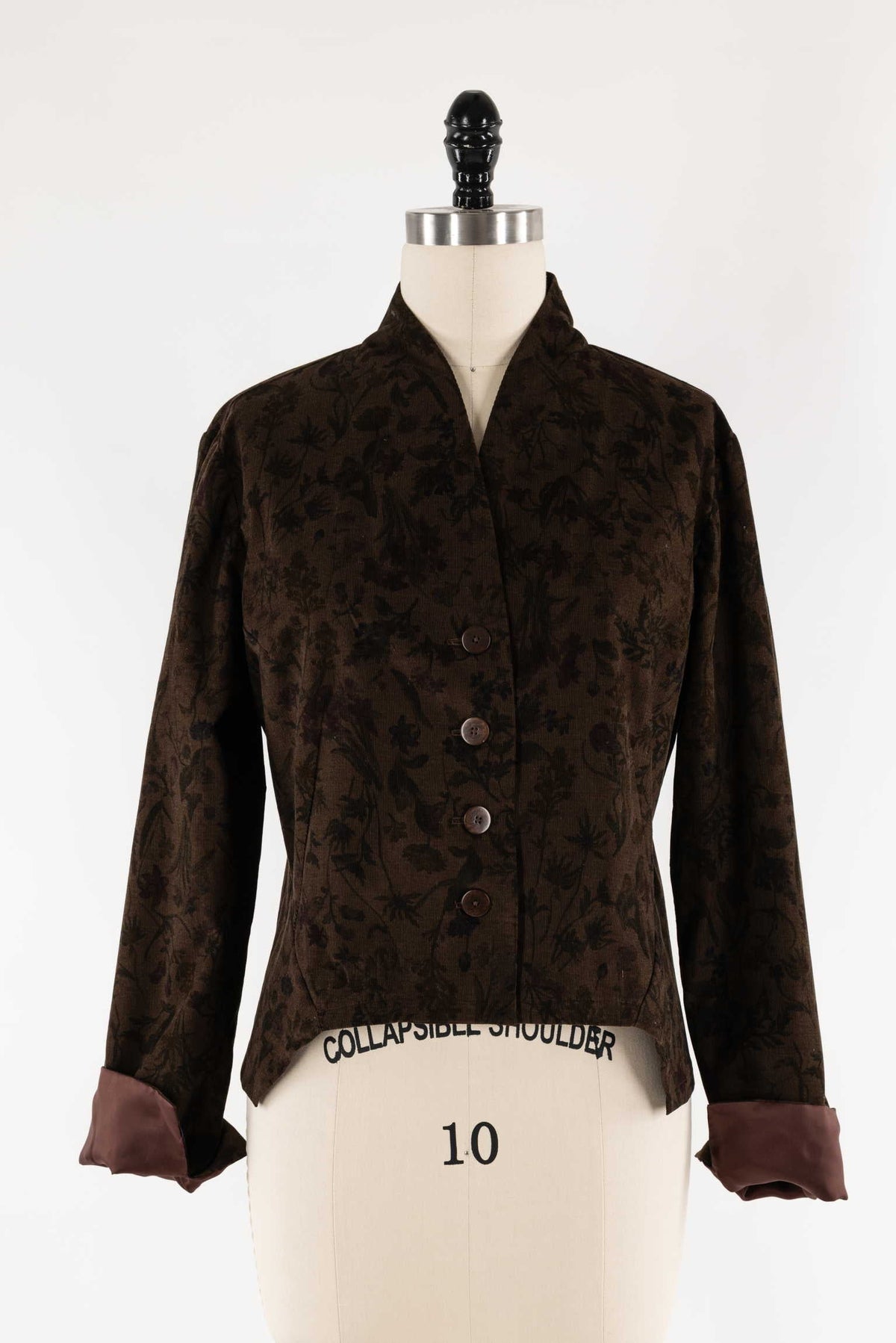 Brown floral corduroy jacket with contrast cuffs on mannequin, ideal for sewing apparel or quilting projects.