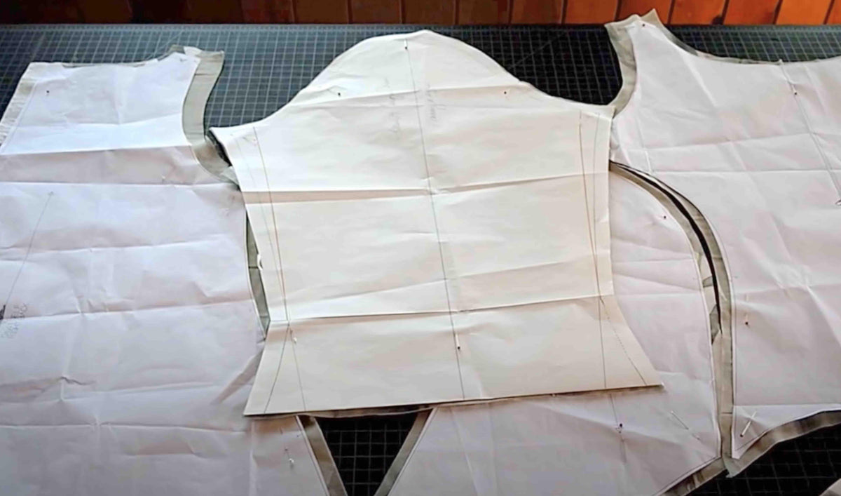 Fabric pattern pieces pinned on cutting mat for sewing project