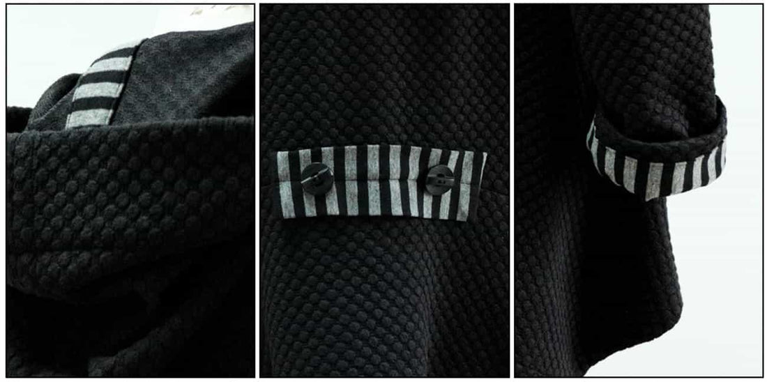 Black textured fabric with striped contrast cuffs and button details, ideal for apparel sewing projects.