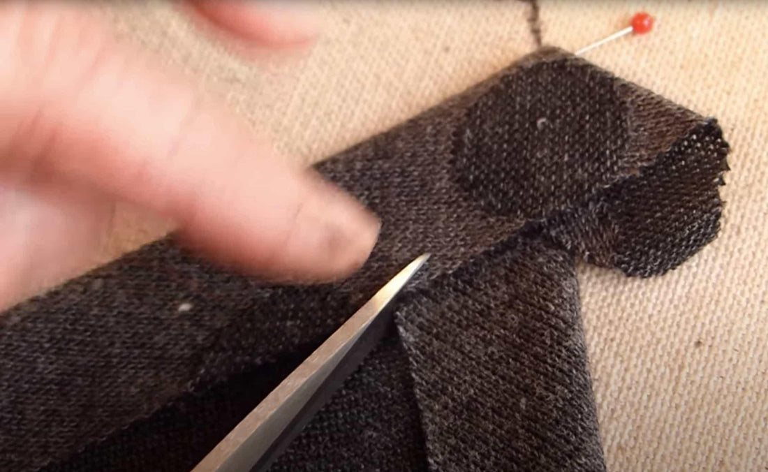 Cutting dark textured knit fabric with scissors for sewing projects