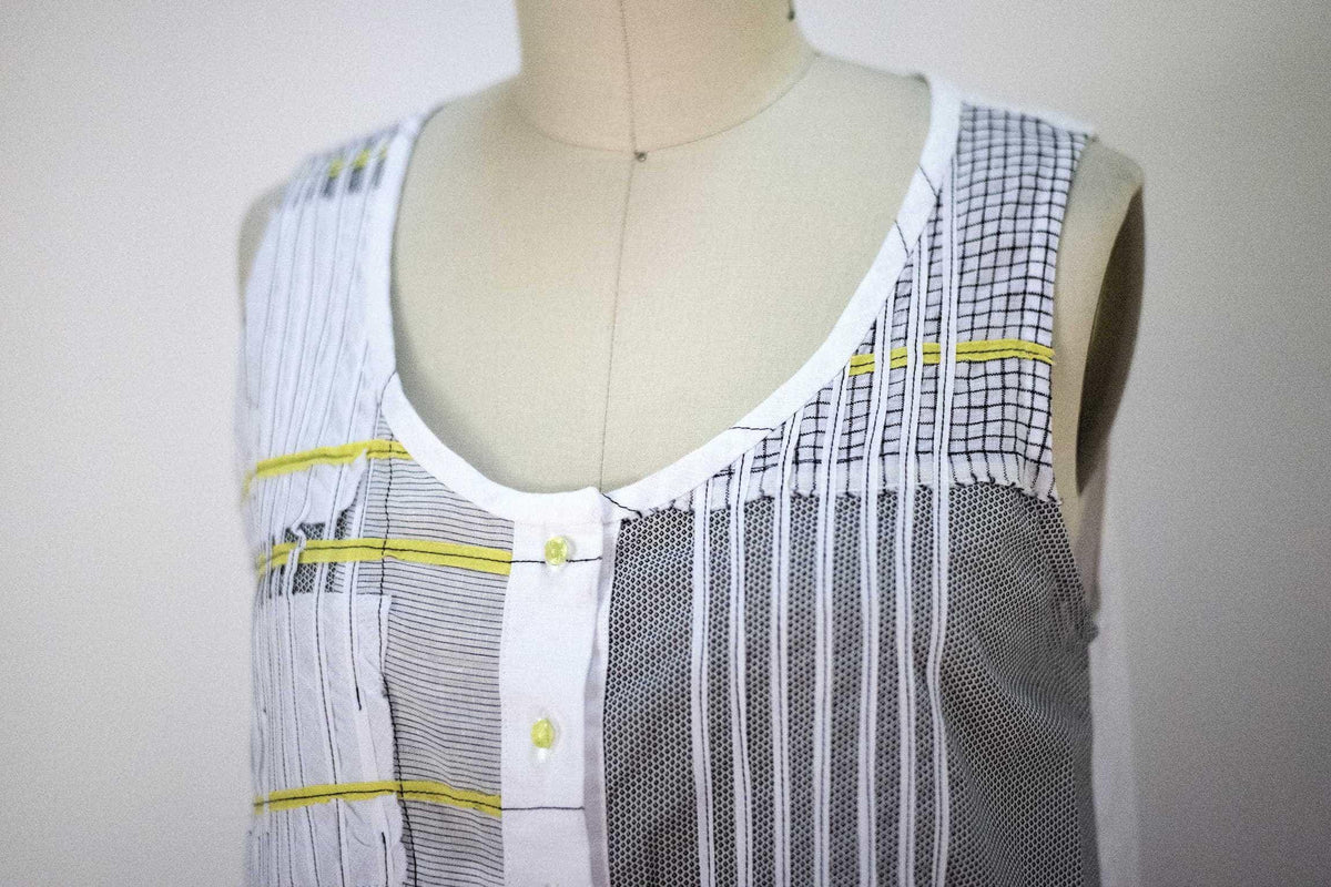 Sleeveless patchwork top with striped, checkered, and mesh panels, yellow accents, and button front