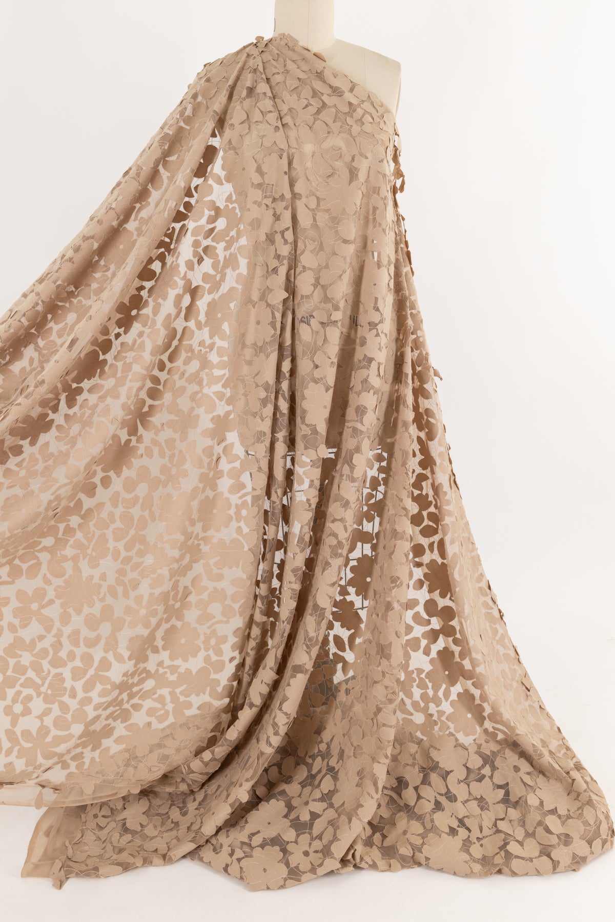 Beige floral lace fabric draped on mannequin, ideal for apparel sewing and fashion projects