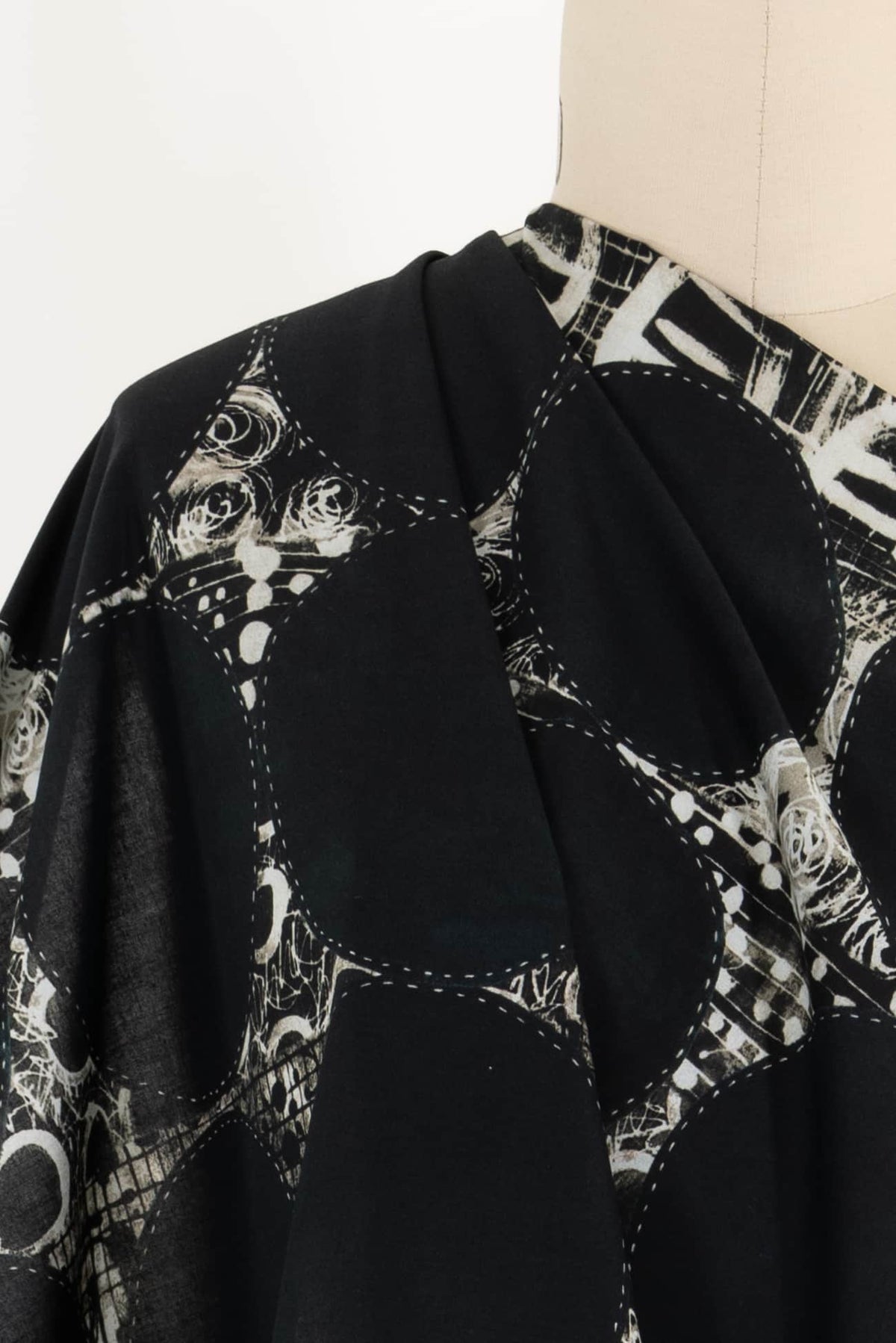 Black fabric with abstract white print and stitched detailing, ideal for apparel sewing projects