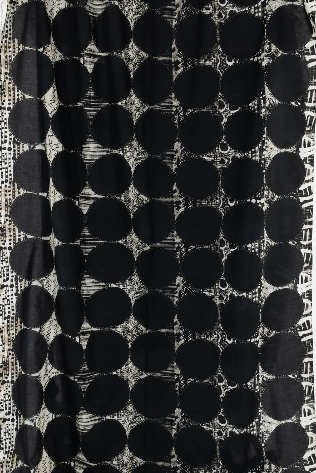 Black and white abstract fabric with bold polka dots and geometric patterns, ideal for apparel sewing