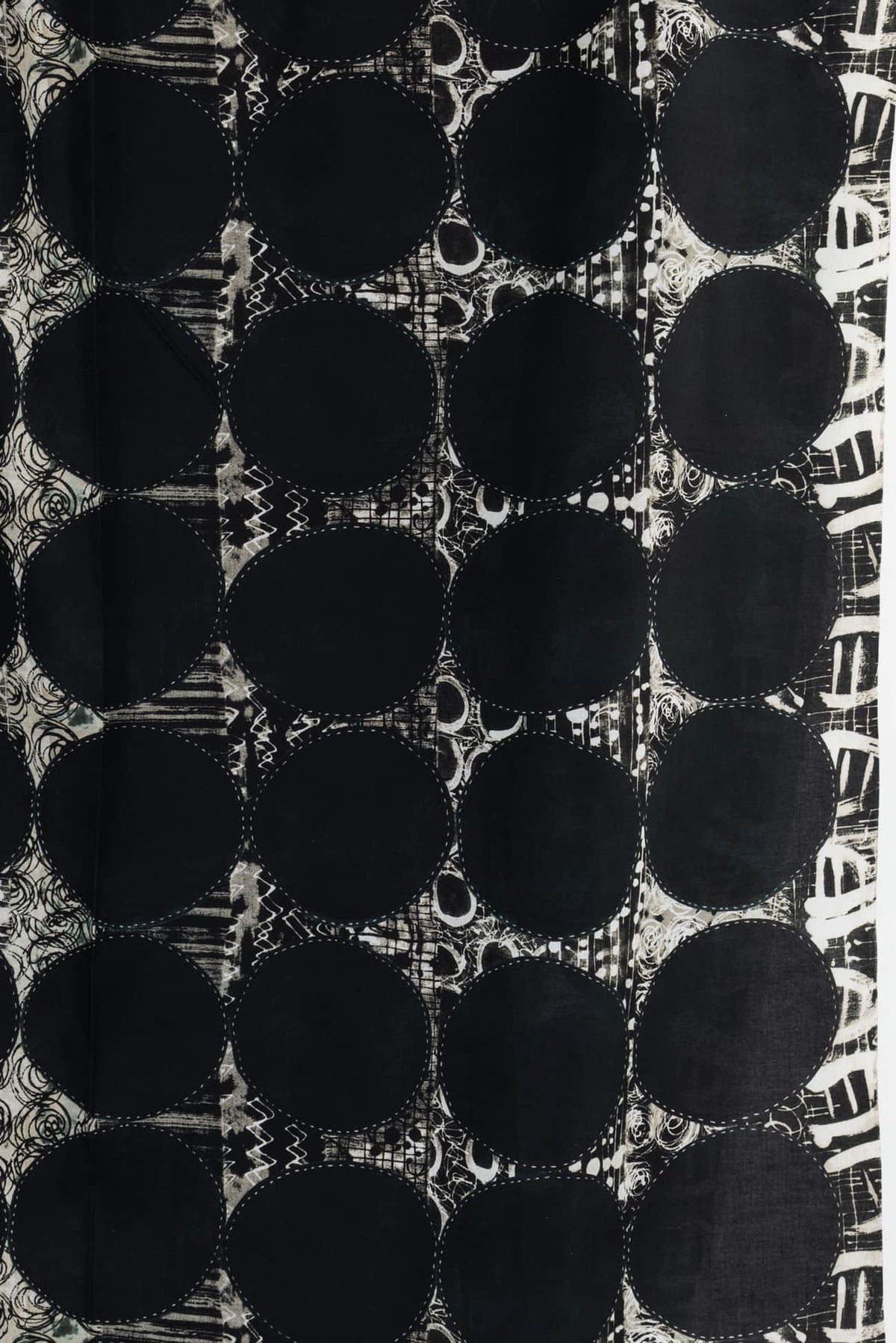 Black and white abstract fabric with bold circles and textured patterns, ideal for apparel and quilting projects.
