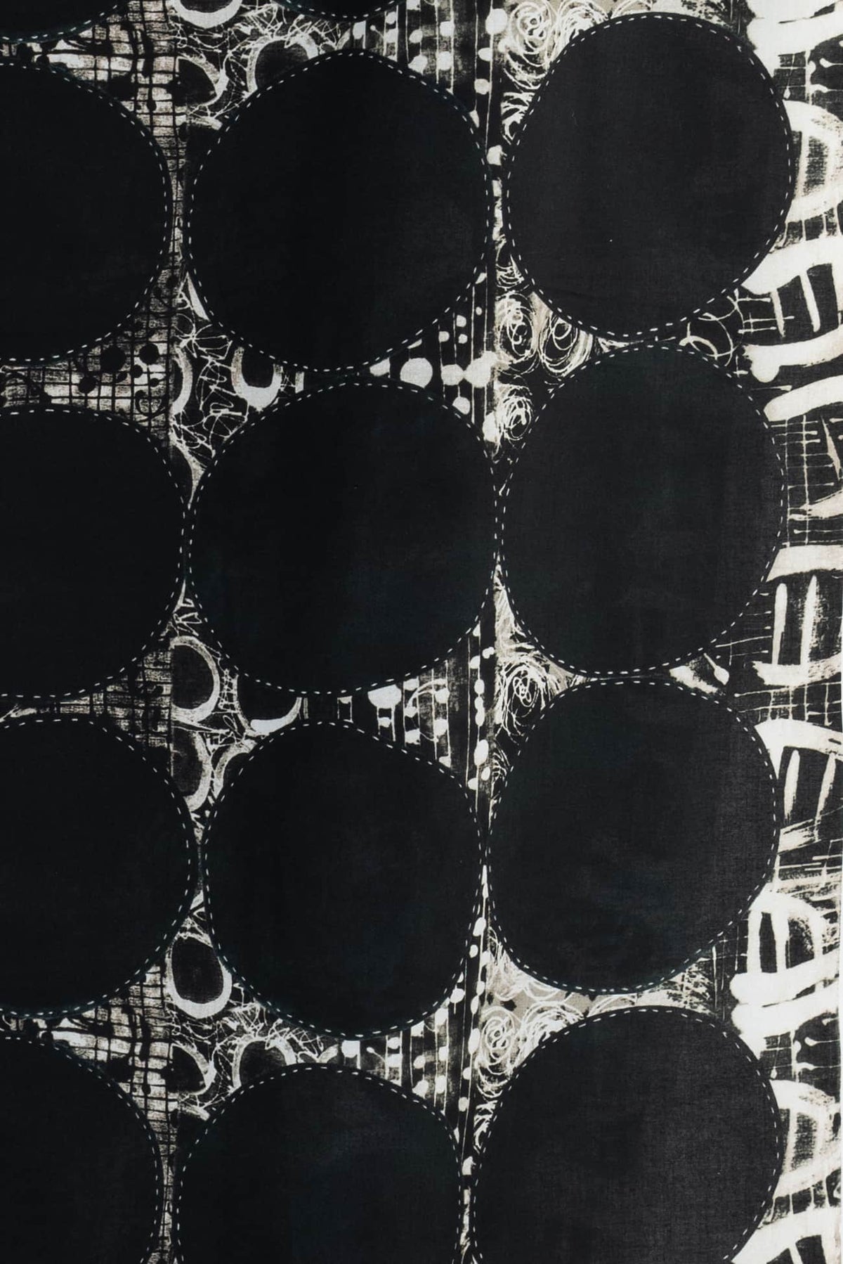 Black and white abstract fabric with bold circles and stitched details, ideal for fashion and apparel sewing projects.