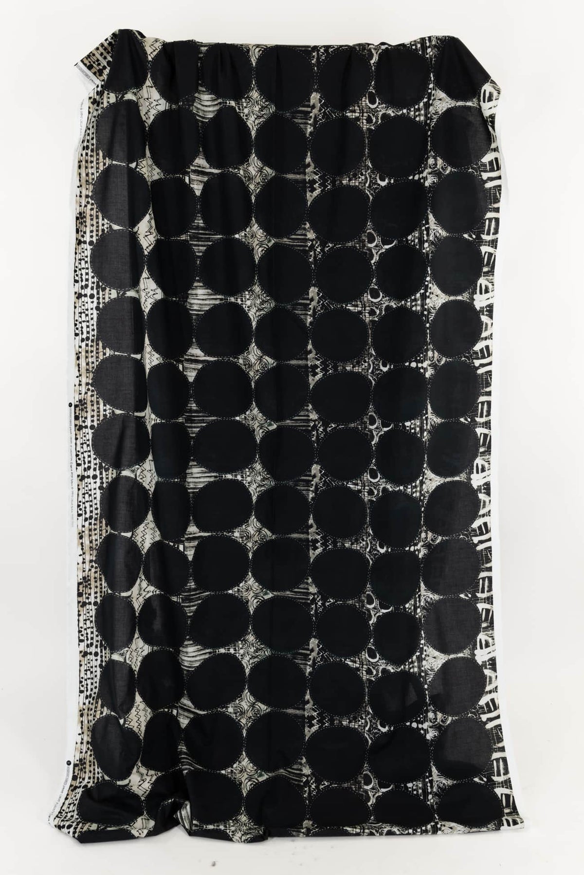 Black and white geometric patterned fabric with bold circles and abstract designs
