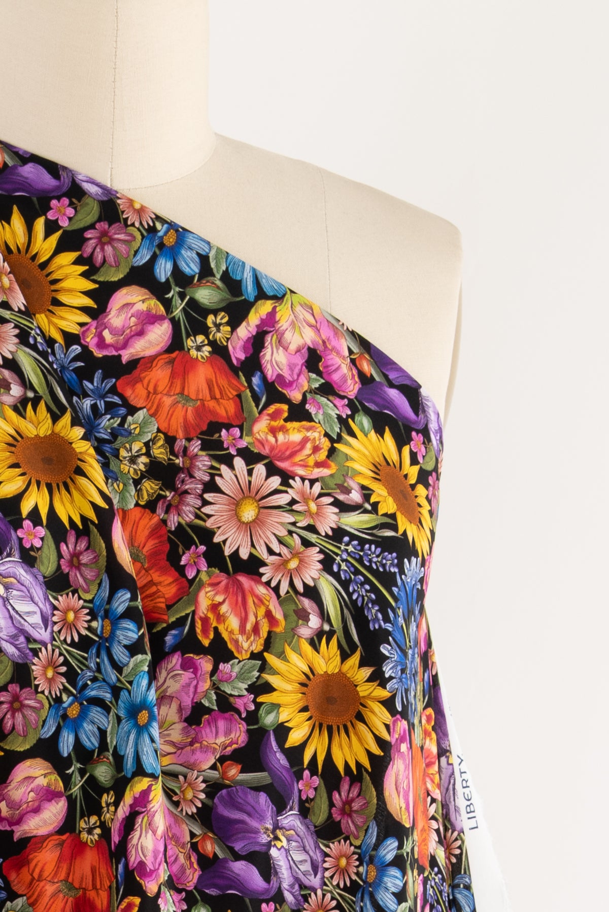 Vibrant floral print fabric with sunflowers, tulips, and daisies on black background, ideal for apparel sewing