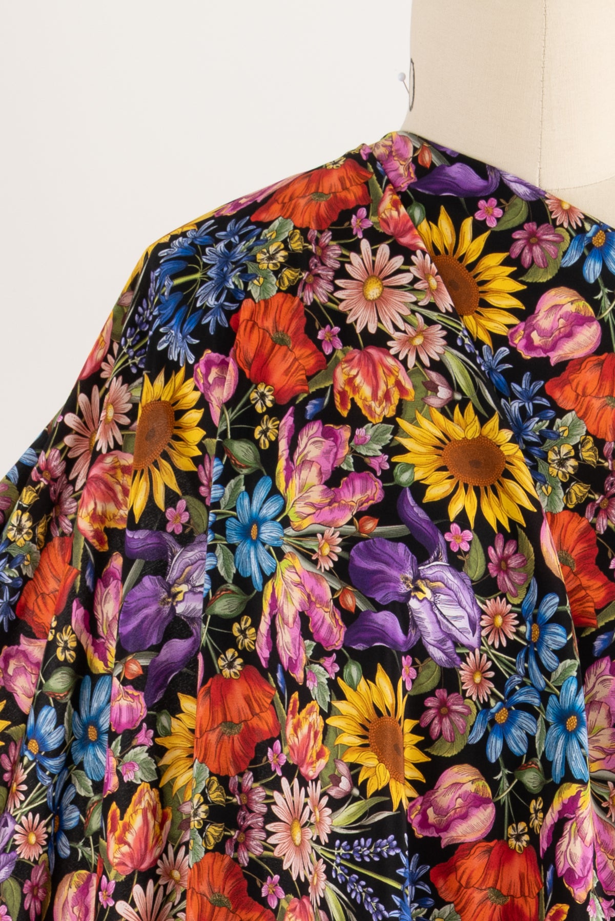 Vibrant floral print fabric with sunflowers, poppies, and irises on black background for sewing projects