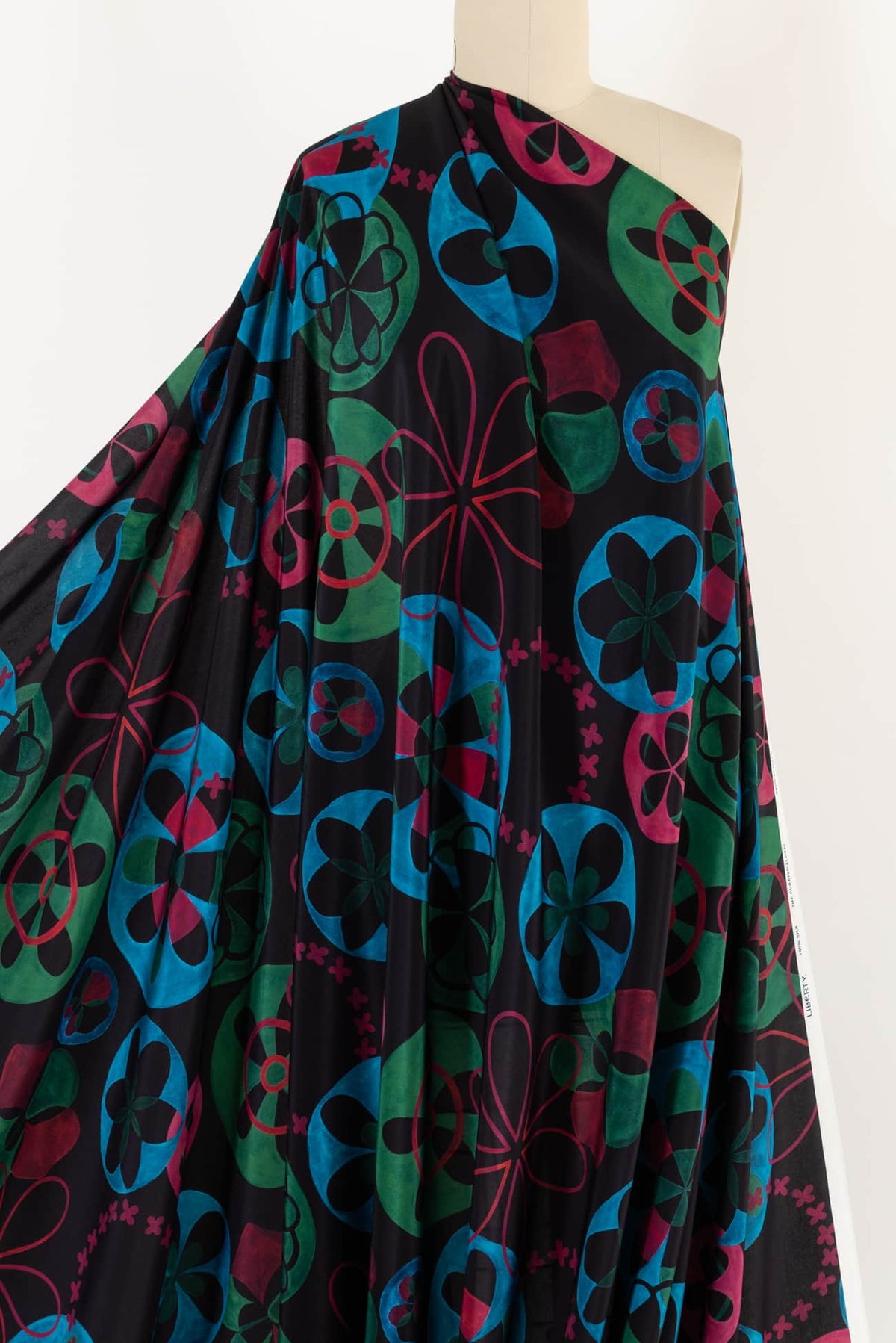Vibrant floral print fabric in teal, green, and pink on black background, ideal for apparel sewing projects.