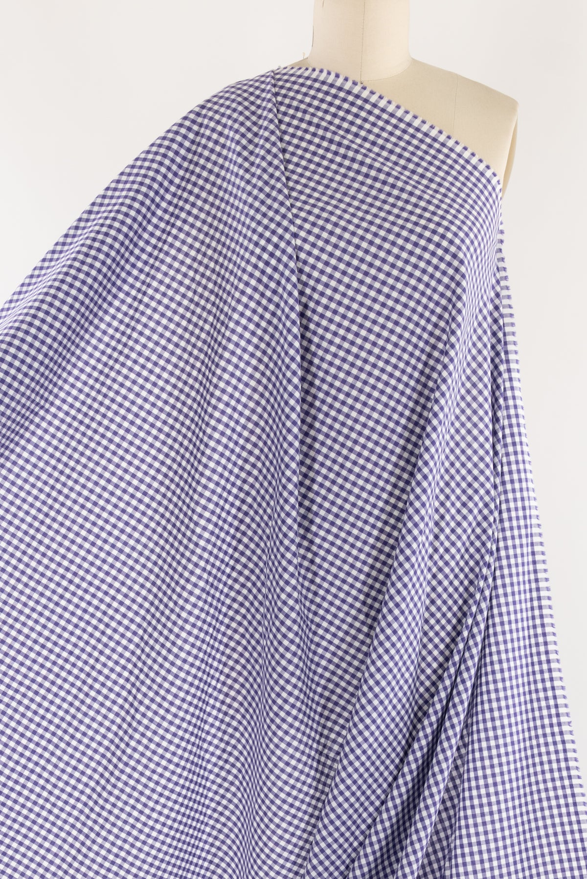 Purple and white gingham check fabric draped on mannequin, ideal for apparel sewing and quilting projects