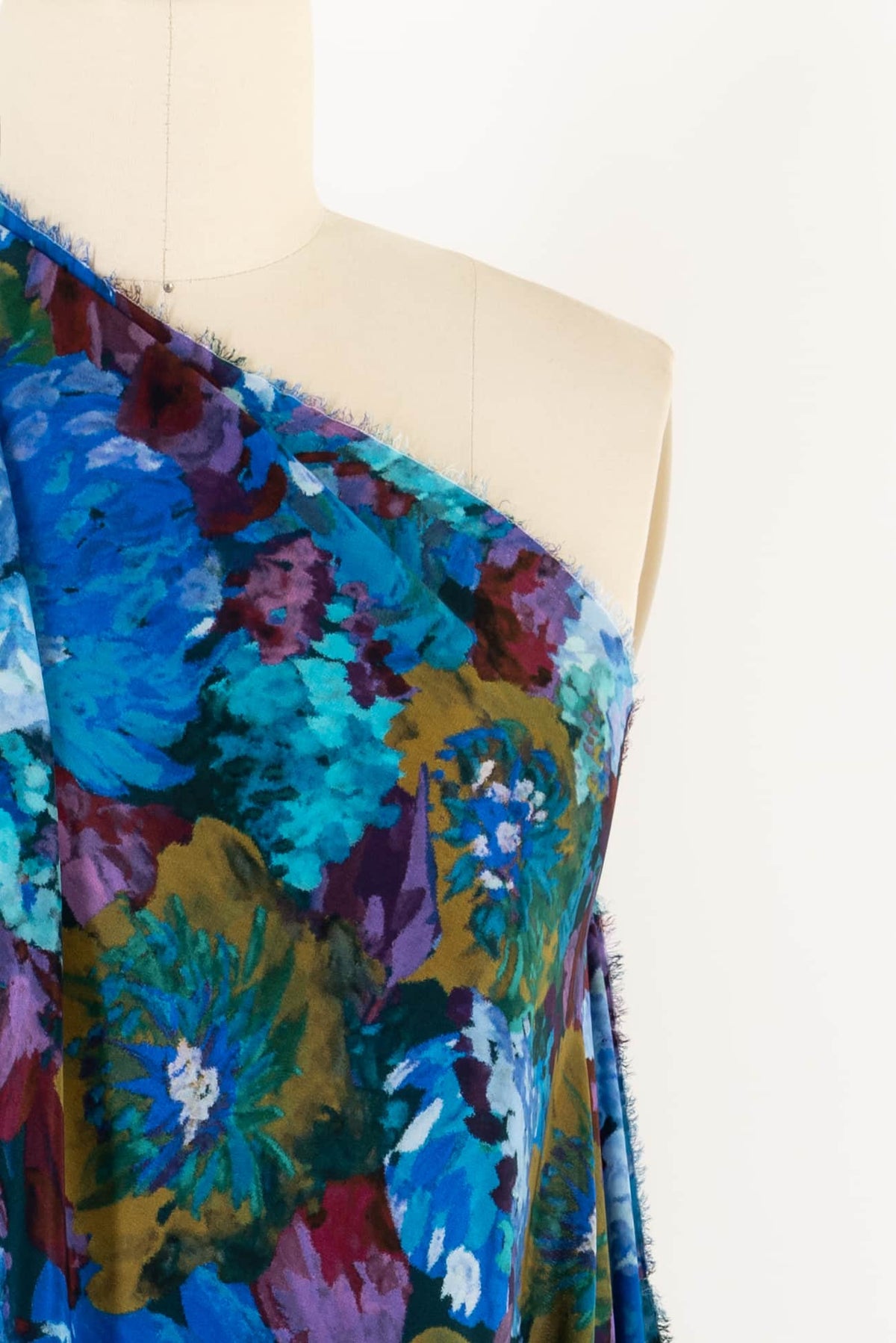 Vibrant floral print fabric in blues, purples, and greens on a mannequin, ideal for apparel sewing projects.