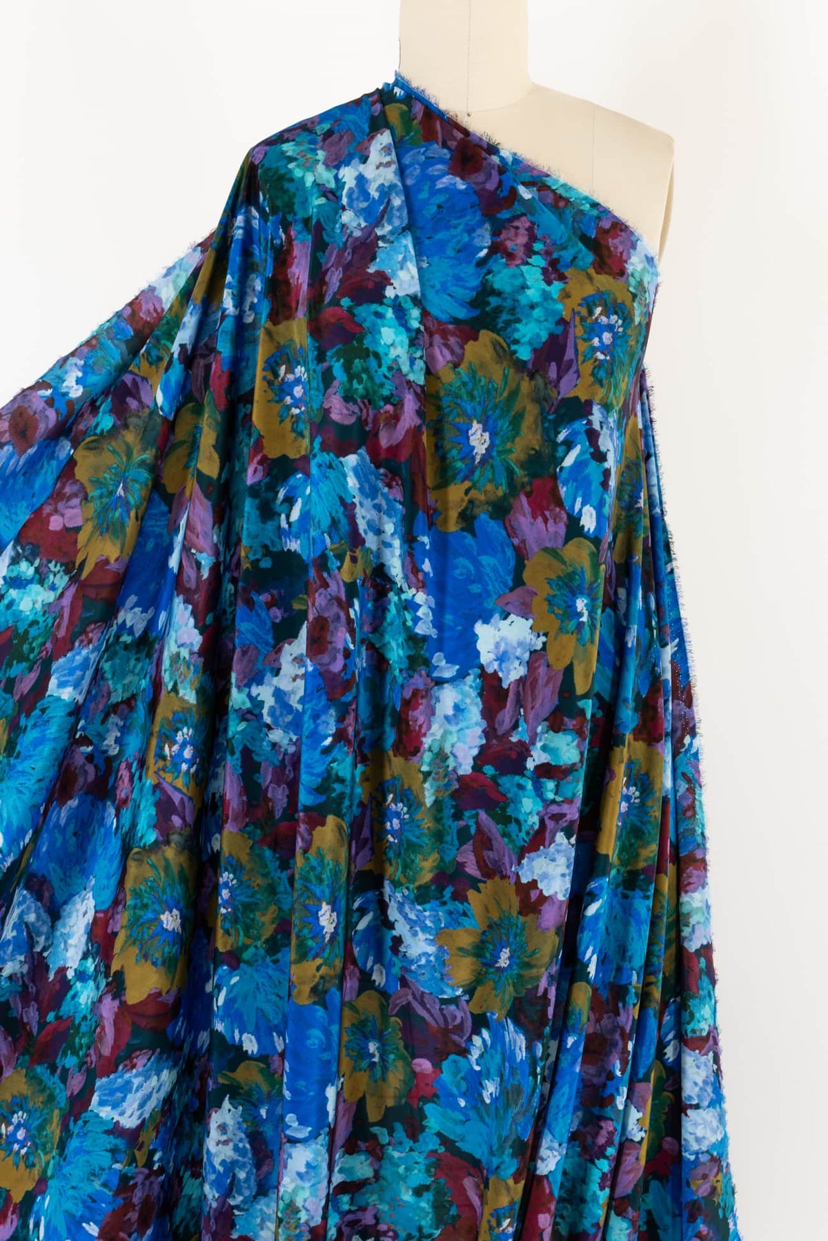 Vibrant floral print fabric in blues, greens, and purples draped on mannequin for apparel sewing