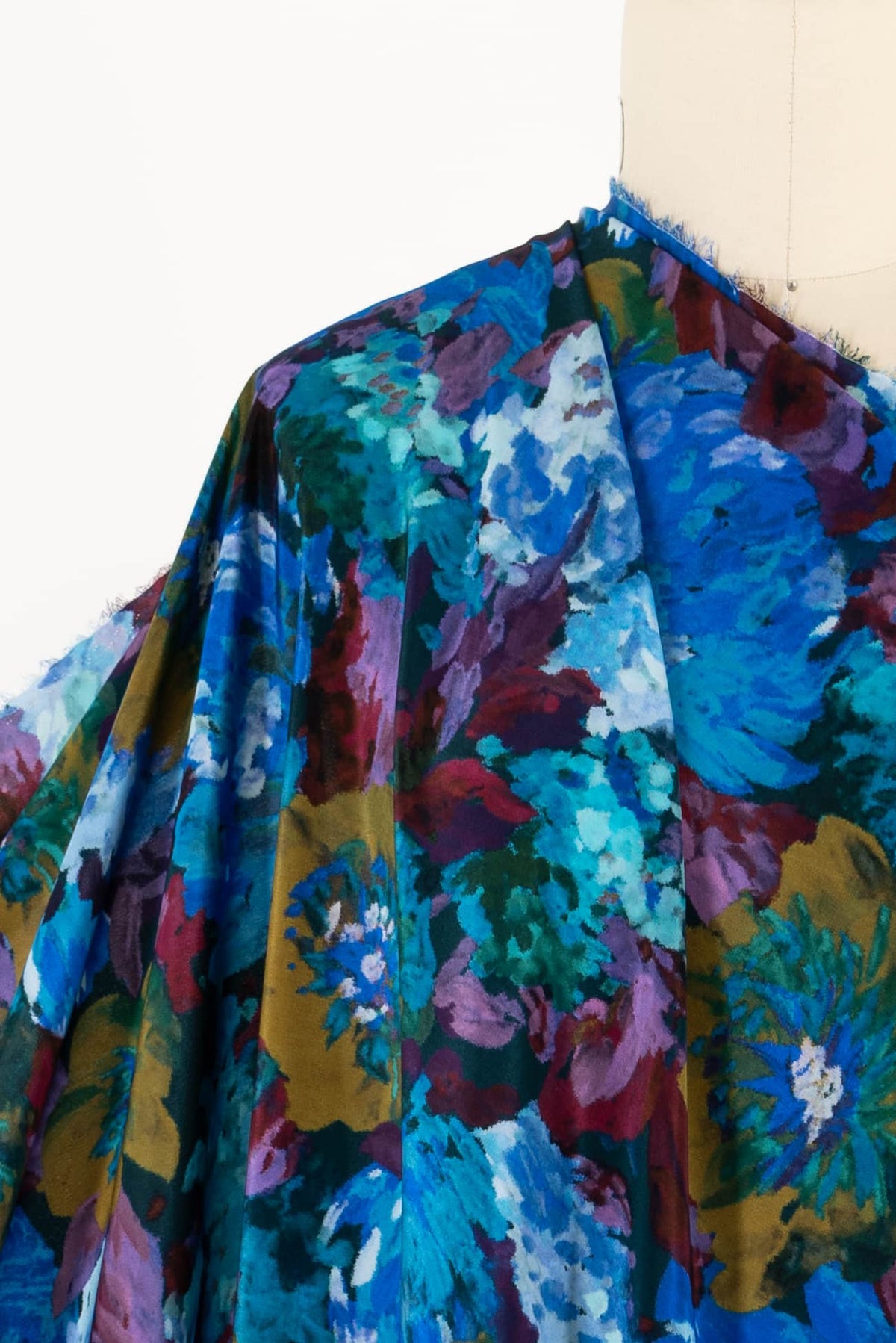 Vibrant floral print fabric in blues, purples, and greens draped on mannequin for apparel sewing