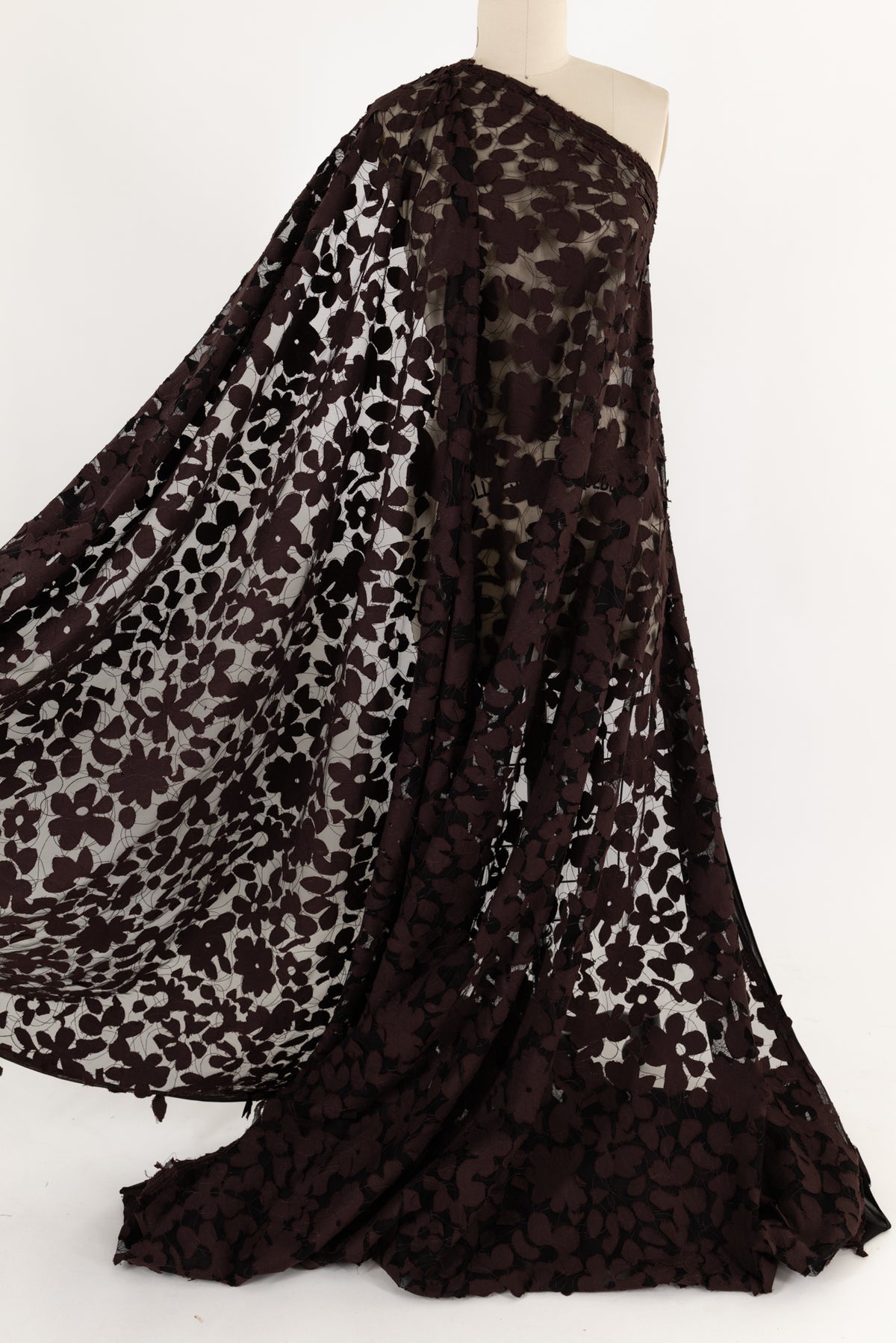 Dark brown floral lace fabric draped on mannequin, ideal for apparel and creative sewing projects