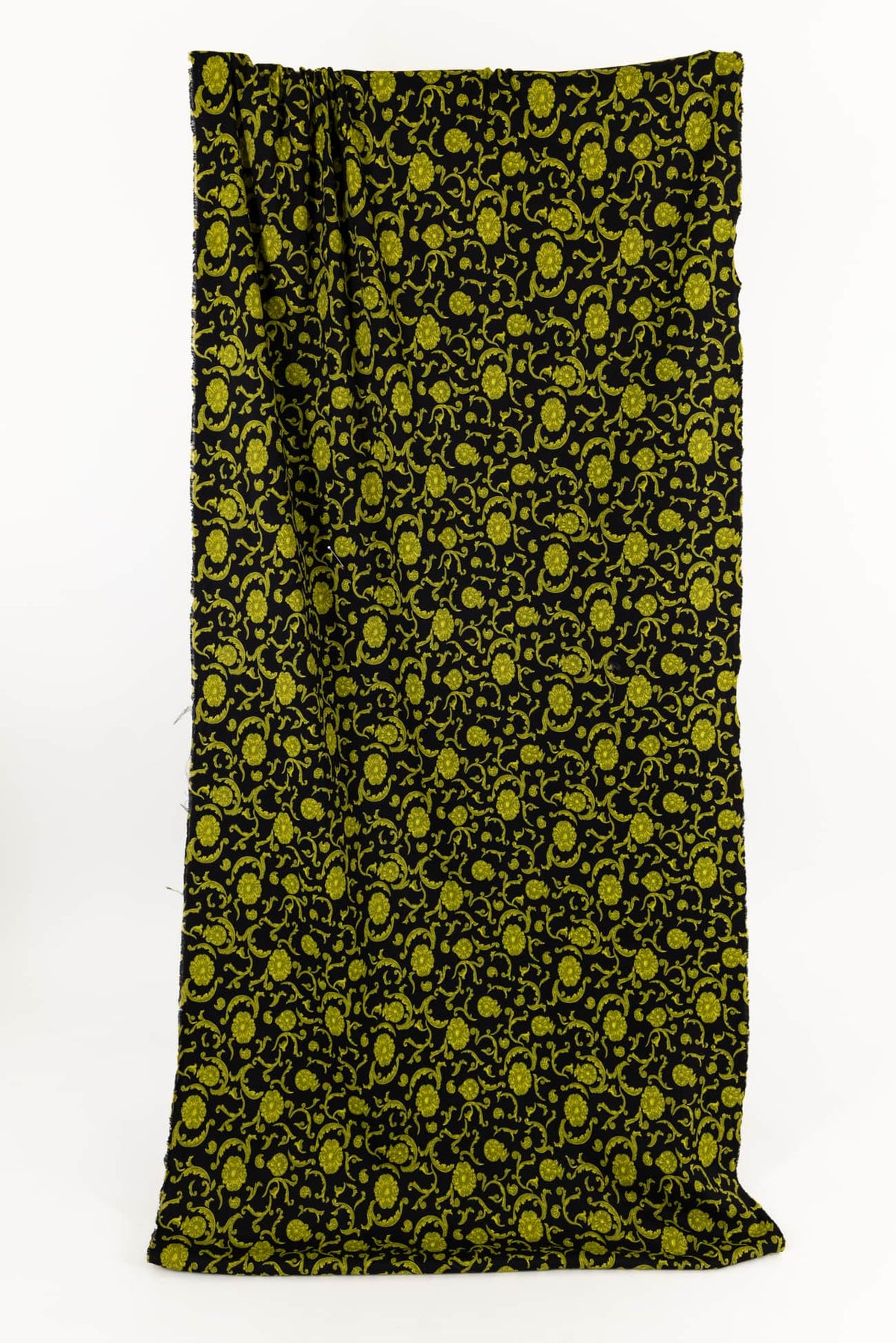 Black fabric with vibrant green floral vine print, ideal for apparel and quilting projects