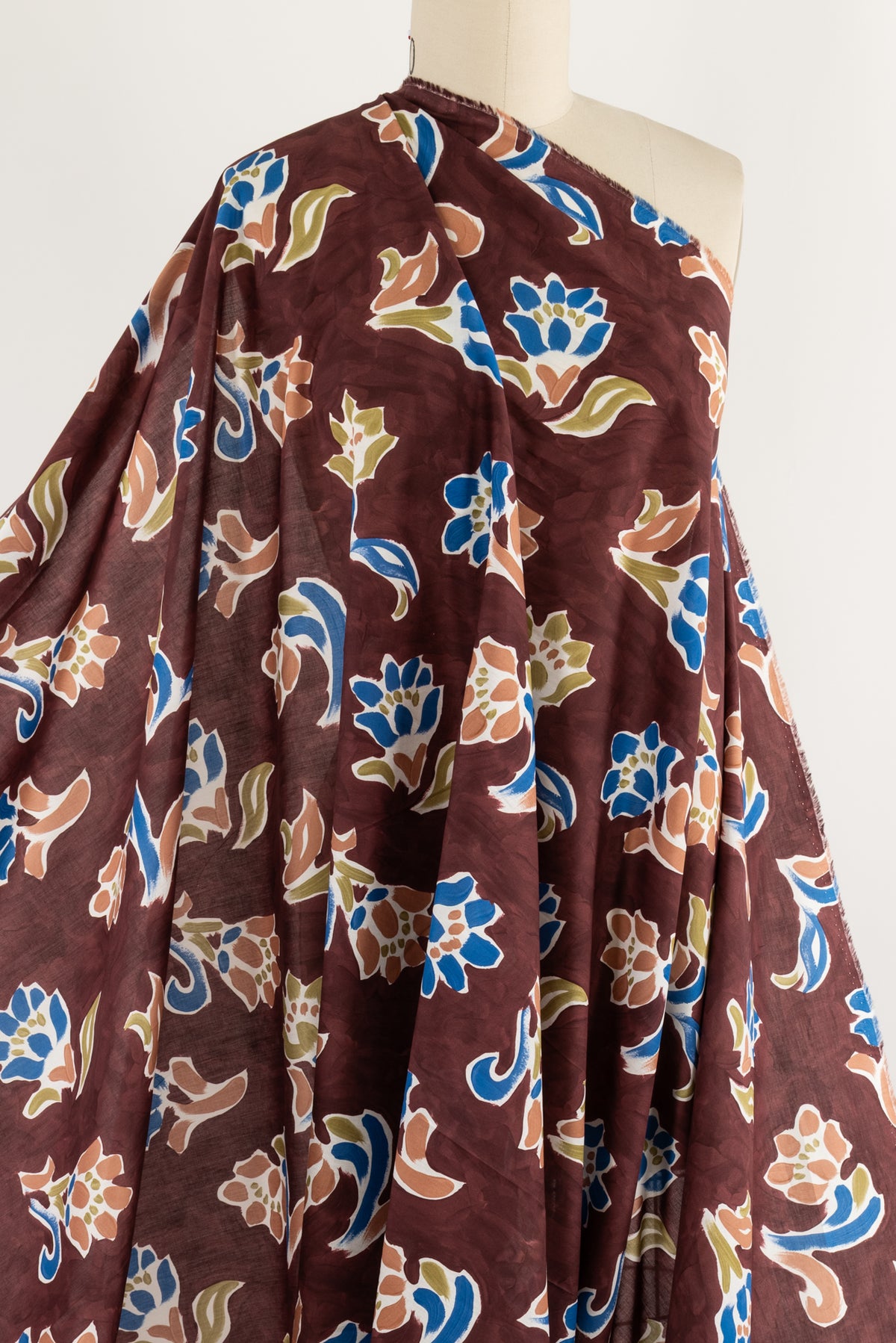 Floral print fabric in burgundy with blue, green, and peach motifs — ideal for apparel and sewing projects