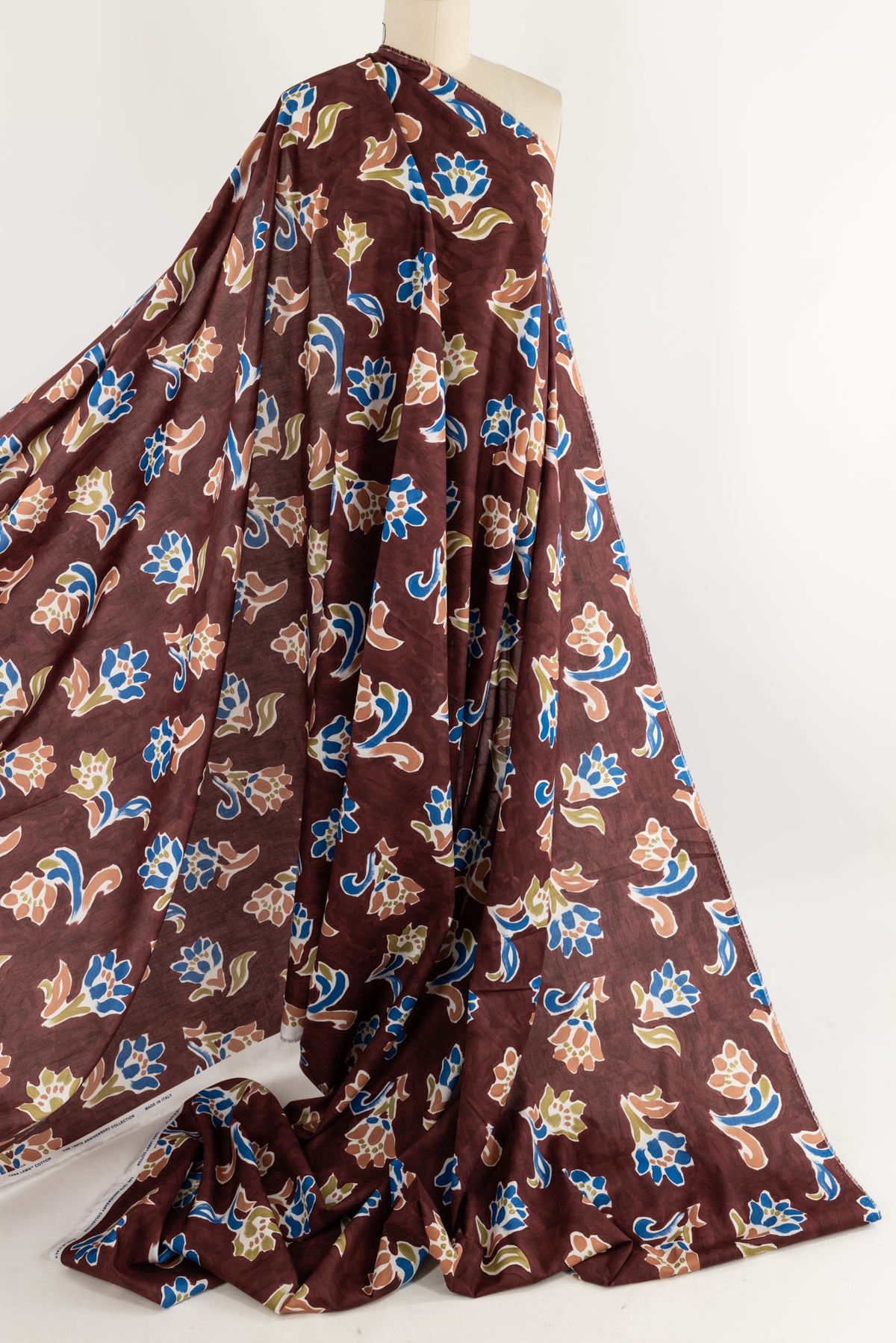 Rich burgundy floral print cotton fabric with blue, peach, and green accents, ideal for apparel and sewing projects.