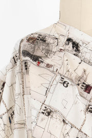 Abstract map print fabric with sketchy lines, numbers, and stamps on cream background for sewing projects