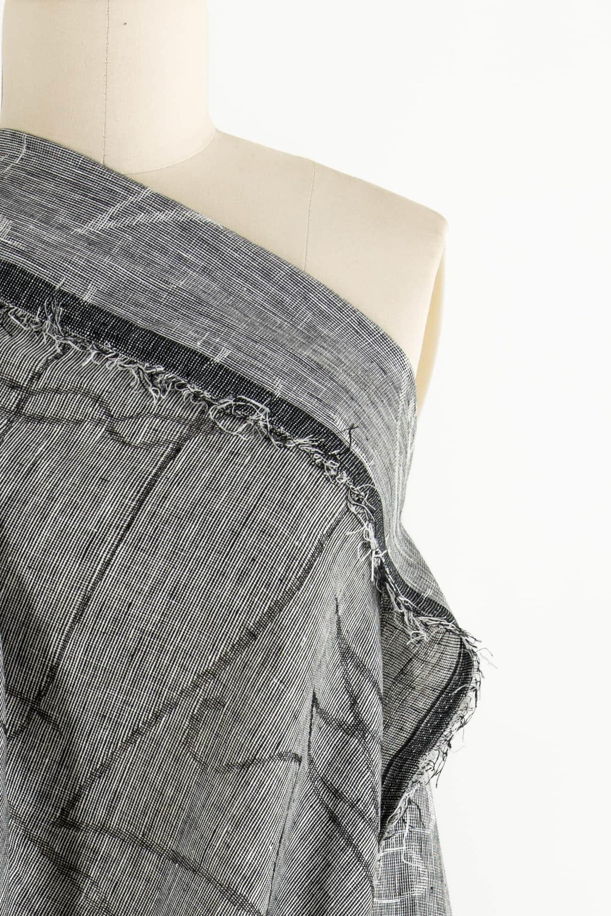 Black and white plaid woven fabric with frayed edge, ideal for apparel sewing projects