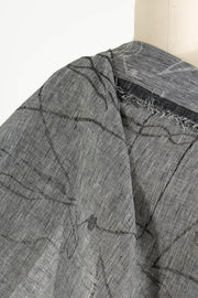 Gray and white striped woven fabric with abstract black lines, draped on mannequin for sewing projects