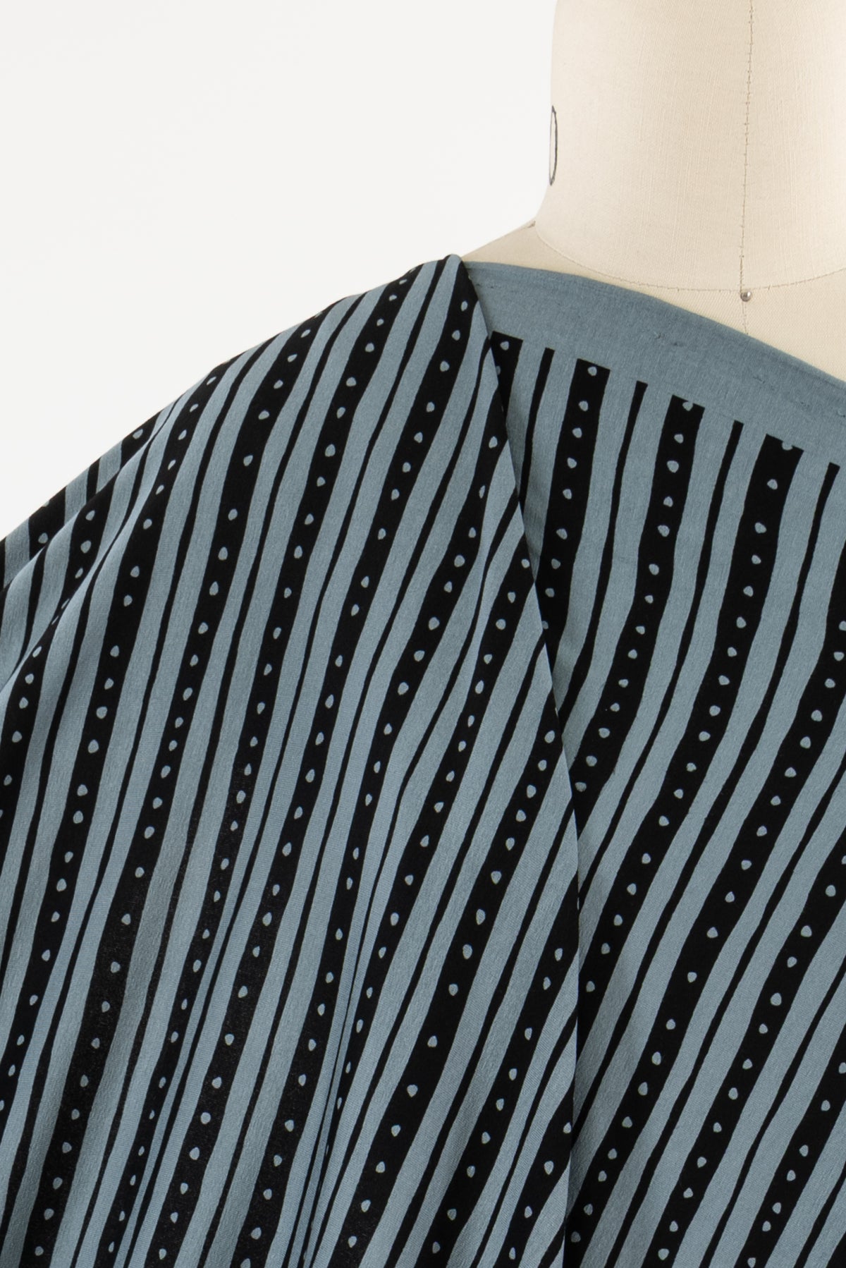 Blue and black striped fabric with white dots, draped on mannequin for apparel sewing